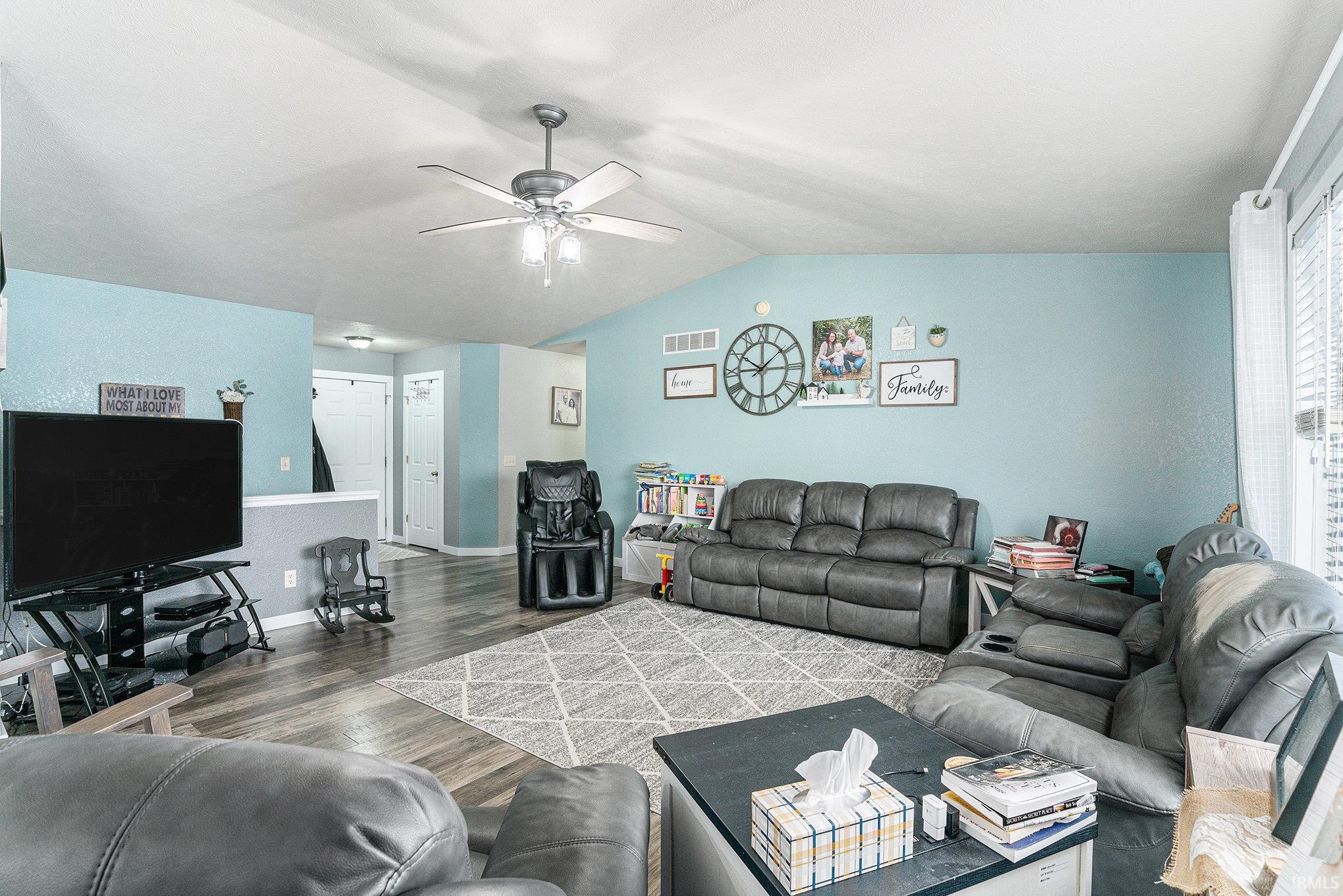 Living area with wood finished floors, lofted ceiling, and ceiling fan