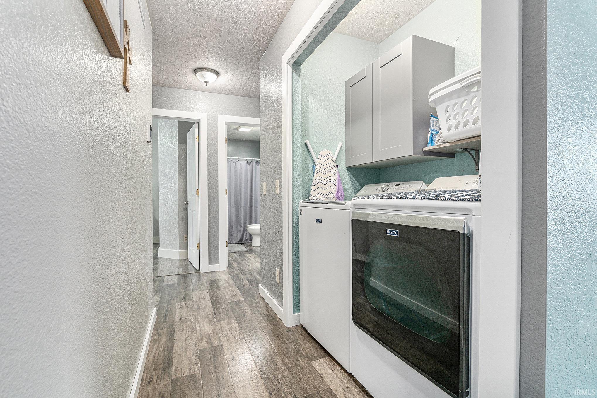 Corridor with a textured wall, dark wood-style floors, a textured ceiling, and washing machine and clothes dryer