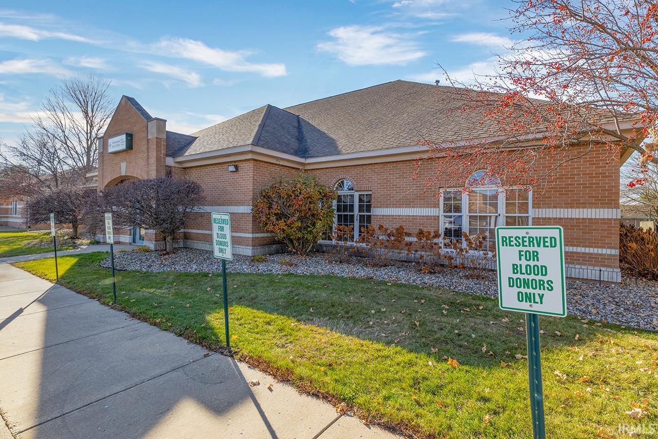 View of front of home with brick siding, roof with shingles, and a front lawn