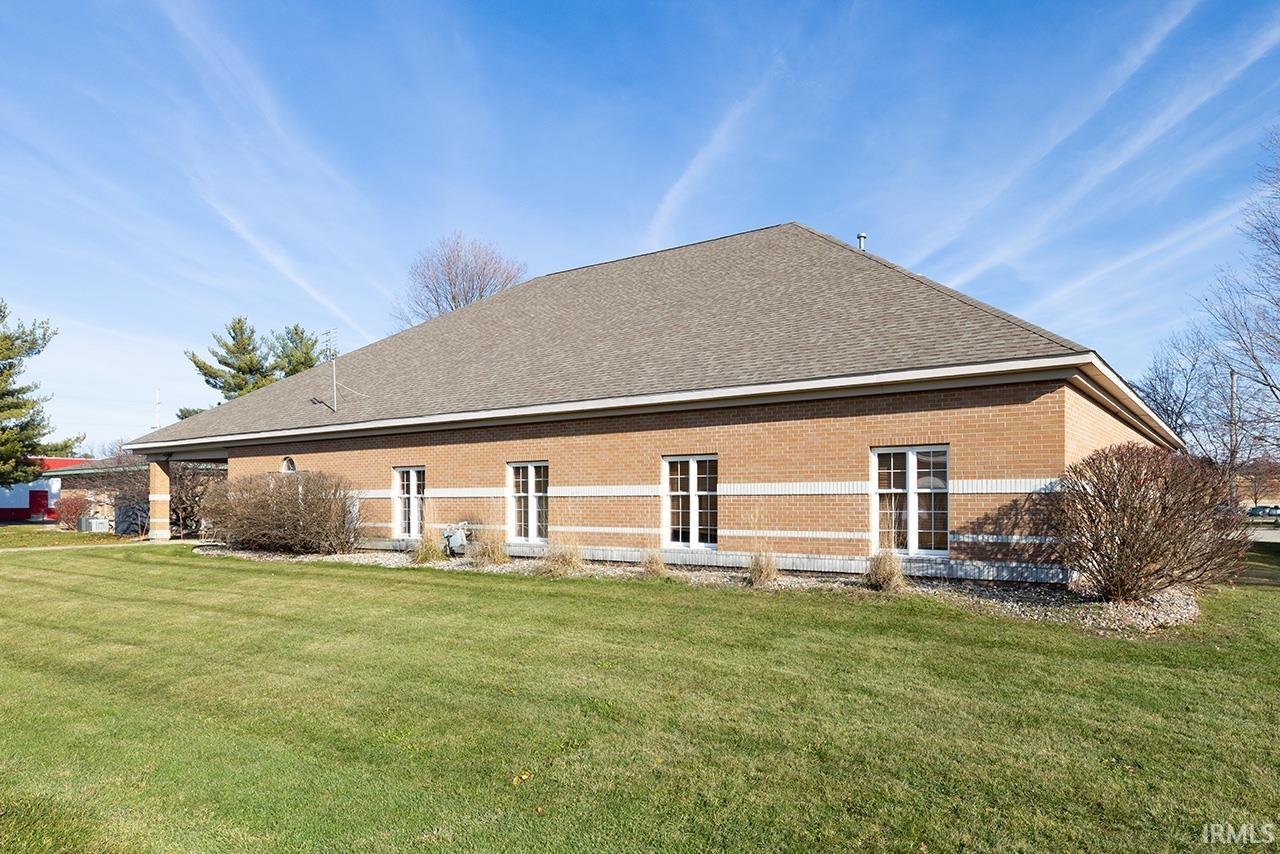 Rear view of house with a yard, brick siding, and a shingled roof