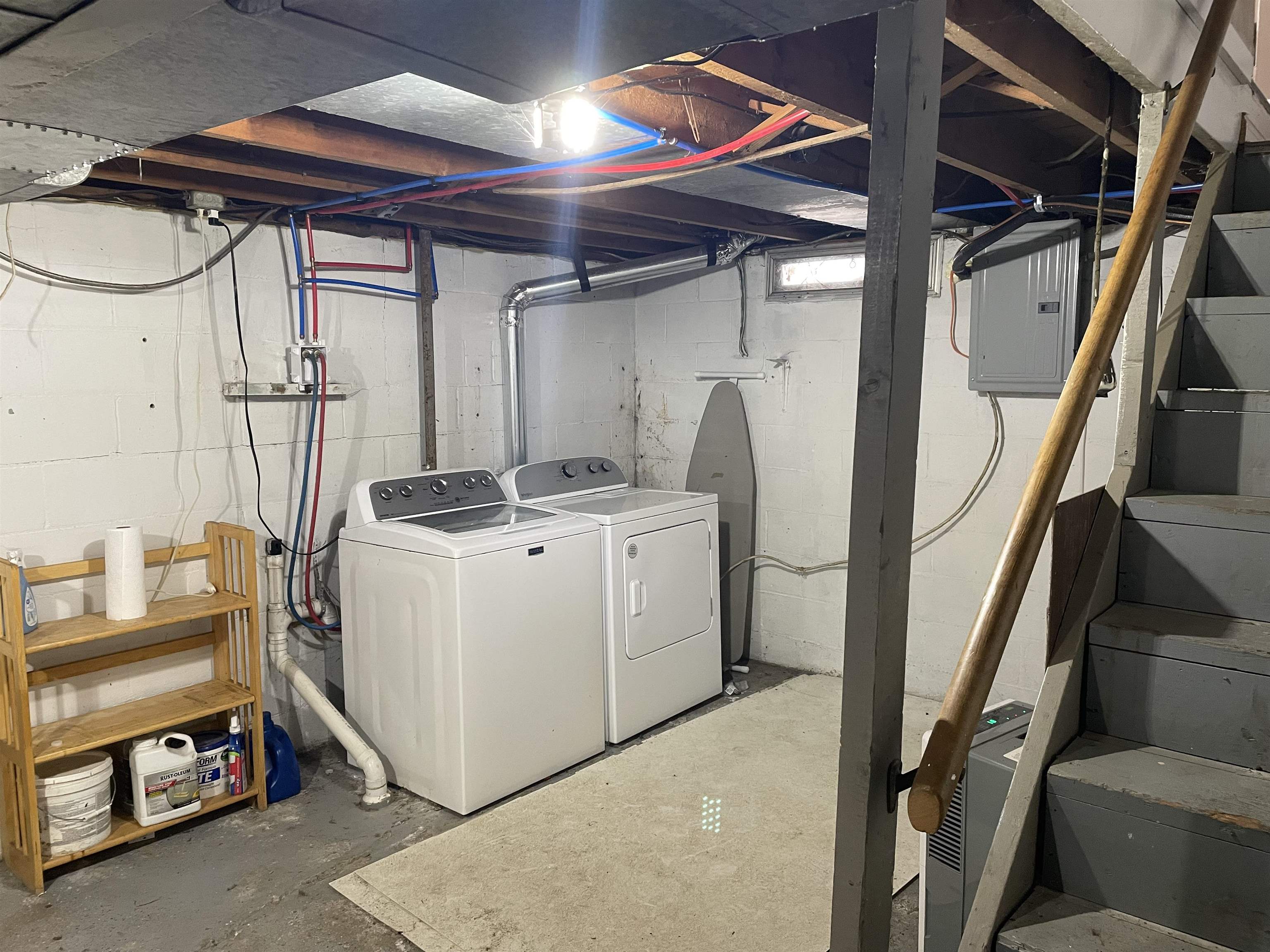 Laundry area featuring unfinished concrete floors, electric panel, and washing machine and clothes dryer