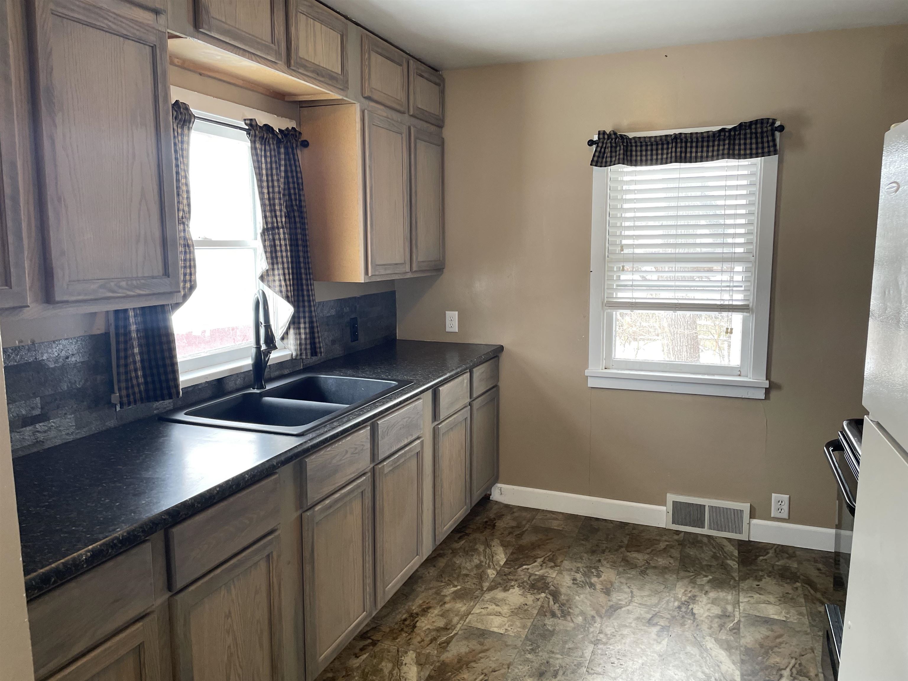 Kitchen featuring dark countertops, freestanding refrigerator, and black range
