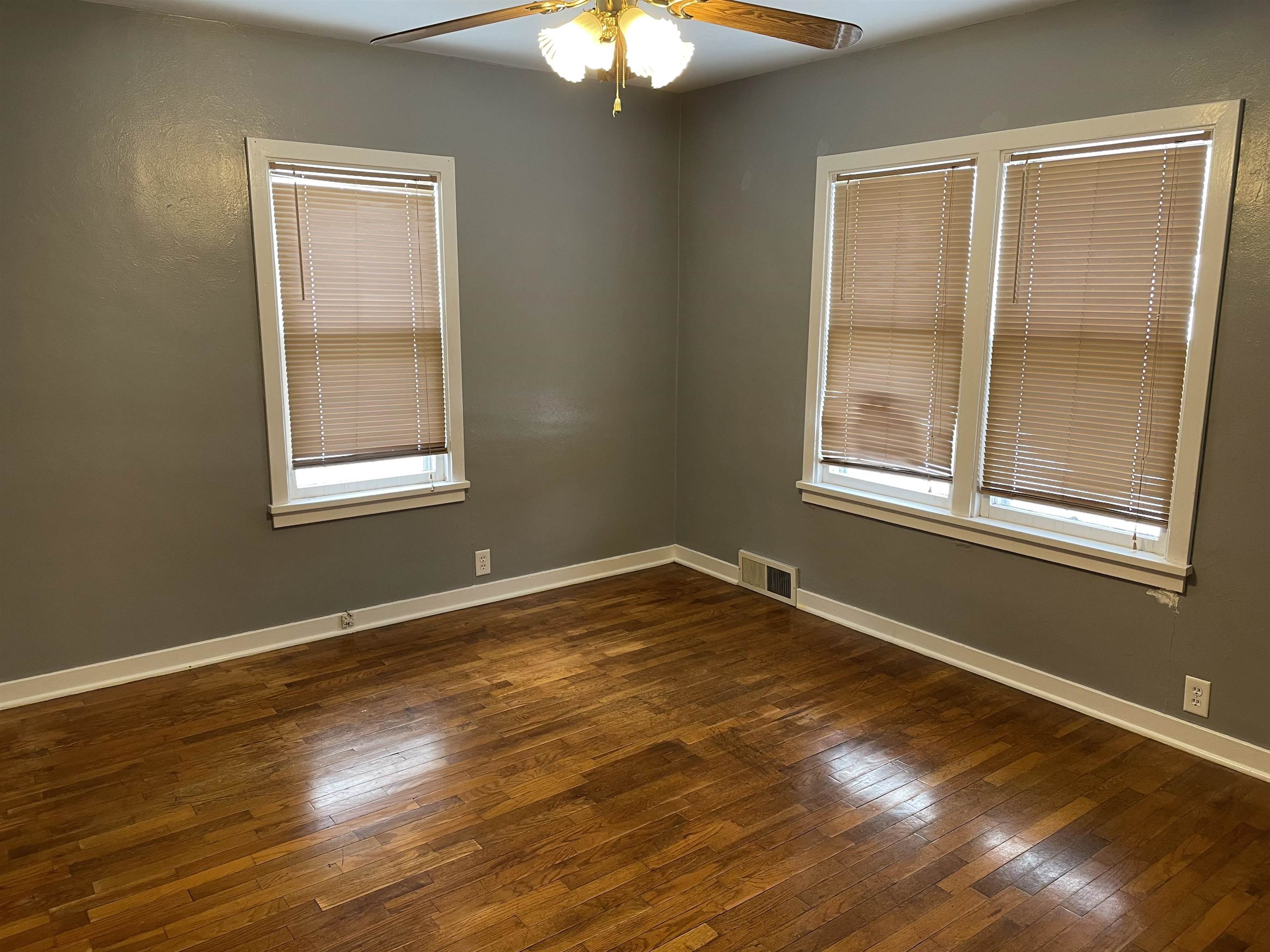 Empty room featuring dark wood-style flooring and a ceiling fan