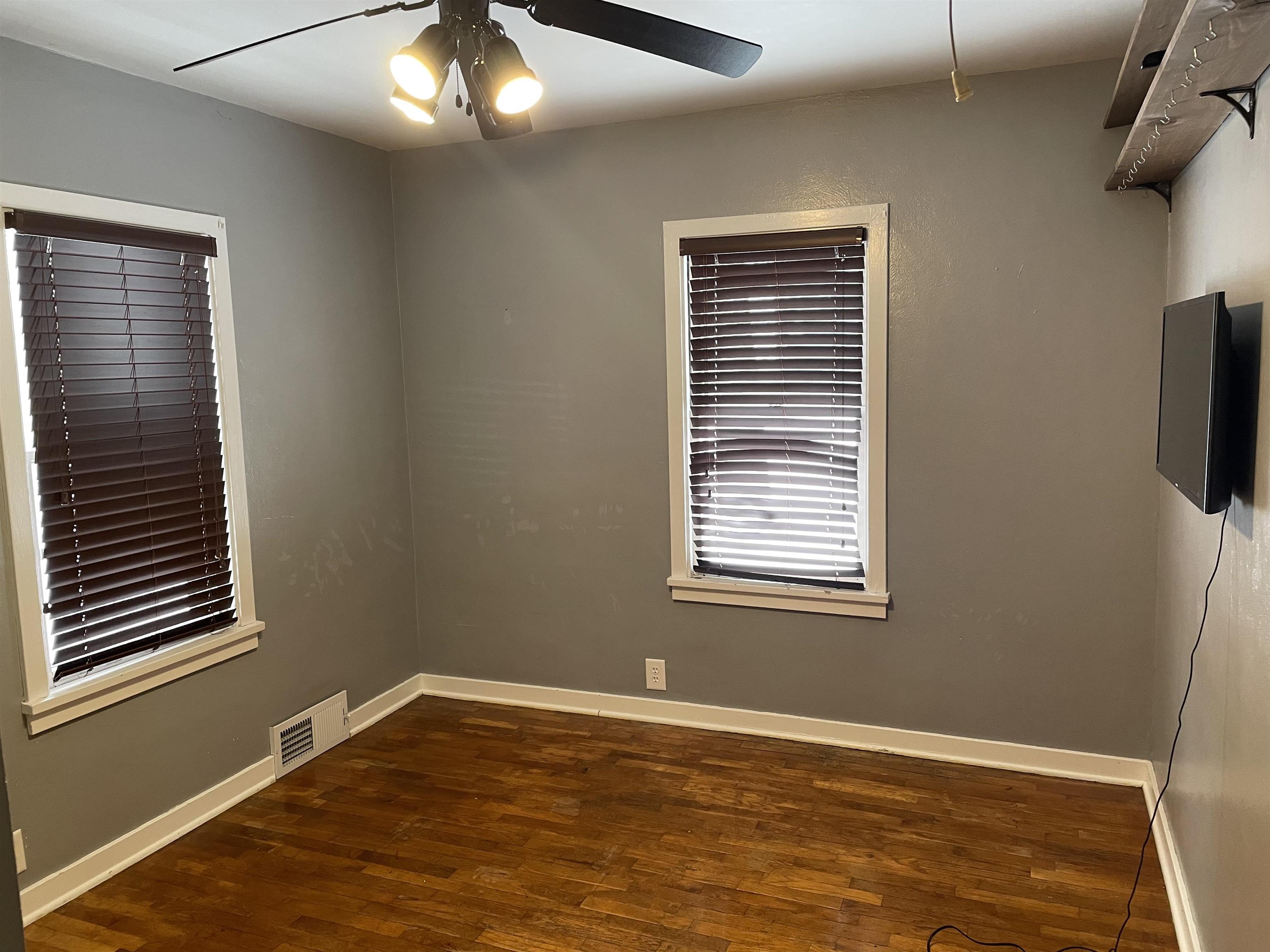 Empty room featuring dark wood finished floors and ceiling fan