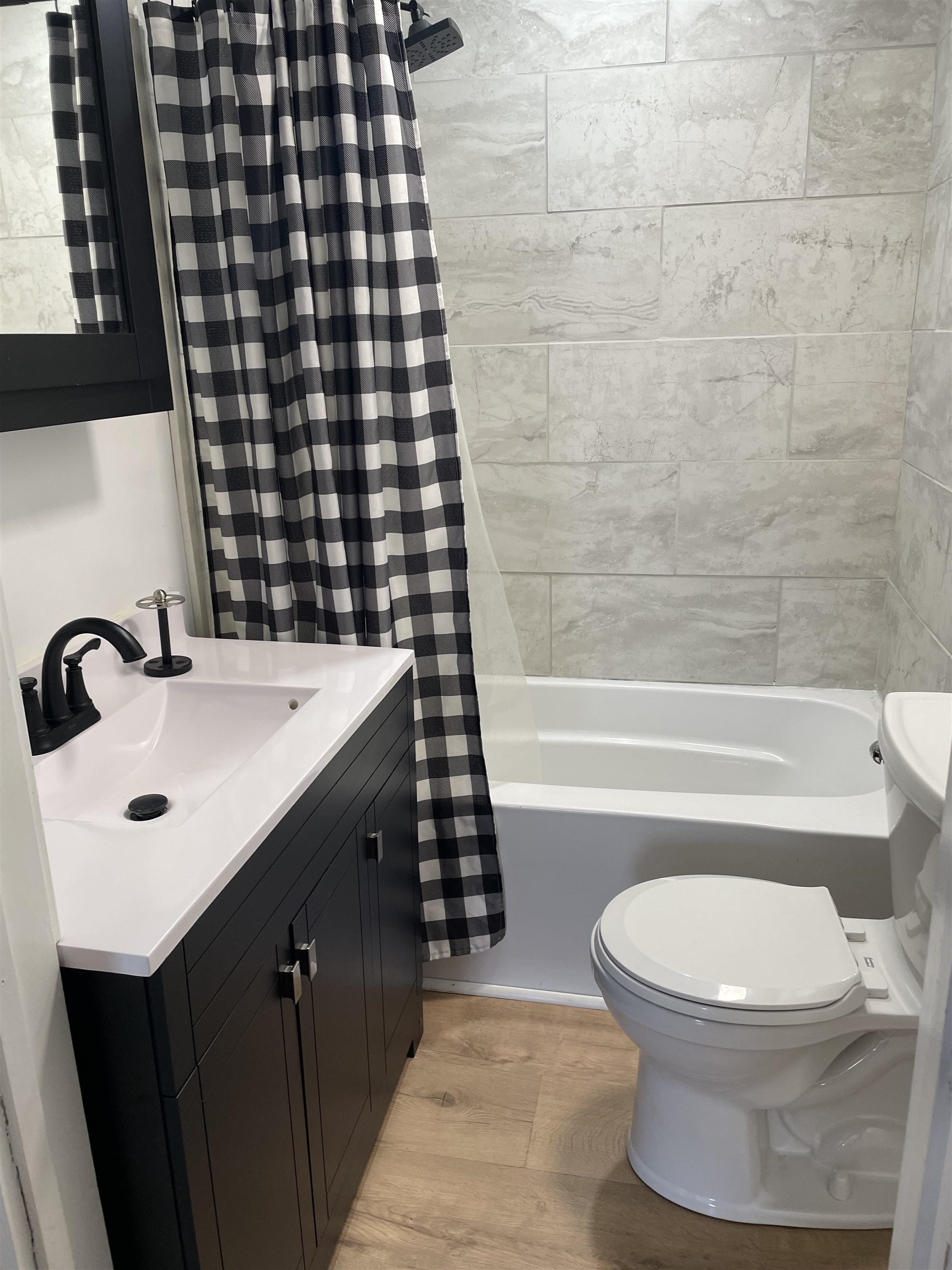 Bathroom featuring vanity, light wood-type flooring, and shower / bathtub combination with curtain