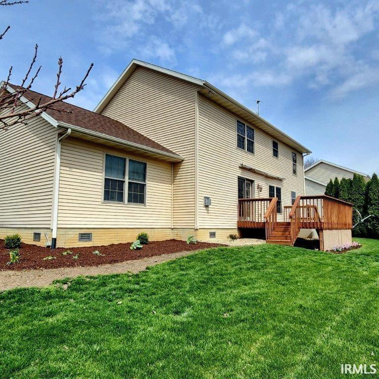 Back of house featuring crawl space, a wooden deck, and a lawn