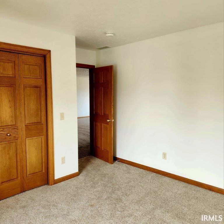 Unfurnished bedroom featuring light colored carpet and a closet