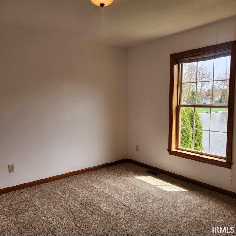 Carpeted spare room featuring baseboards