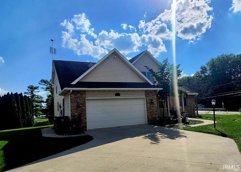 View of property exterior with concrete driveway, brick siding, a garage, and a yard
