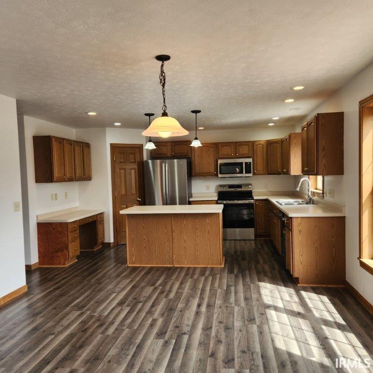 Kitchen featuring decorative light fixtures, stainless steel appliances, light countertops, recessed lighting, and a center island