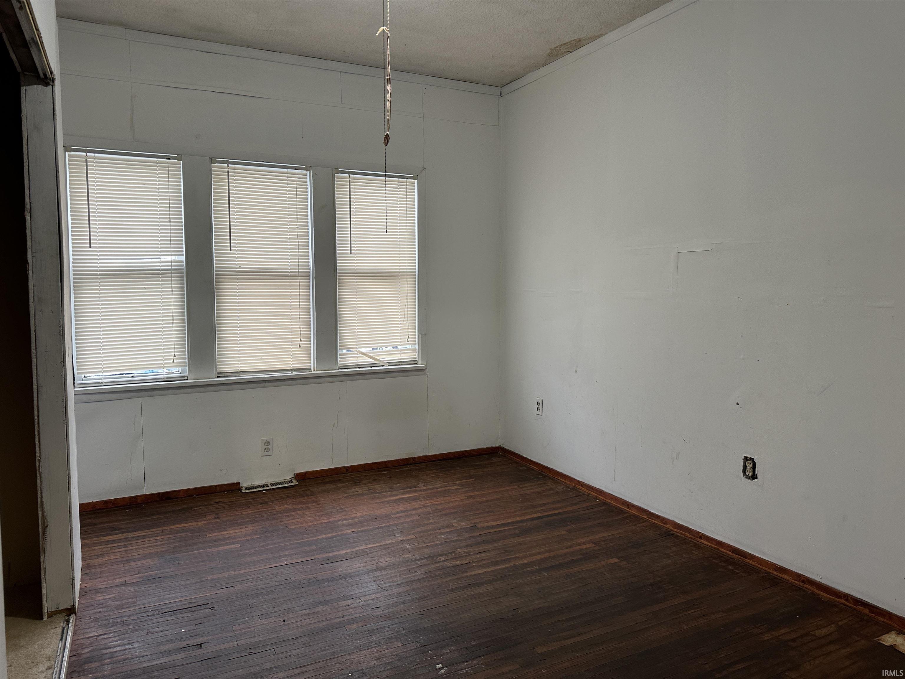 Empty room with dark wood-style floors and crown molding