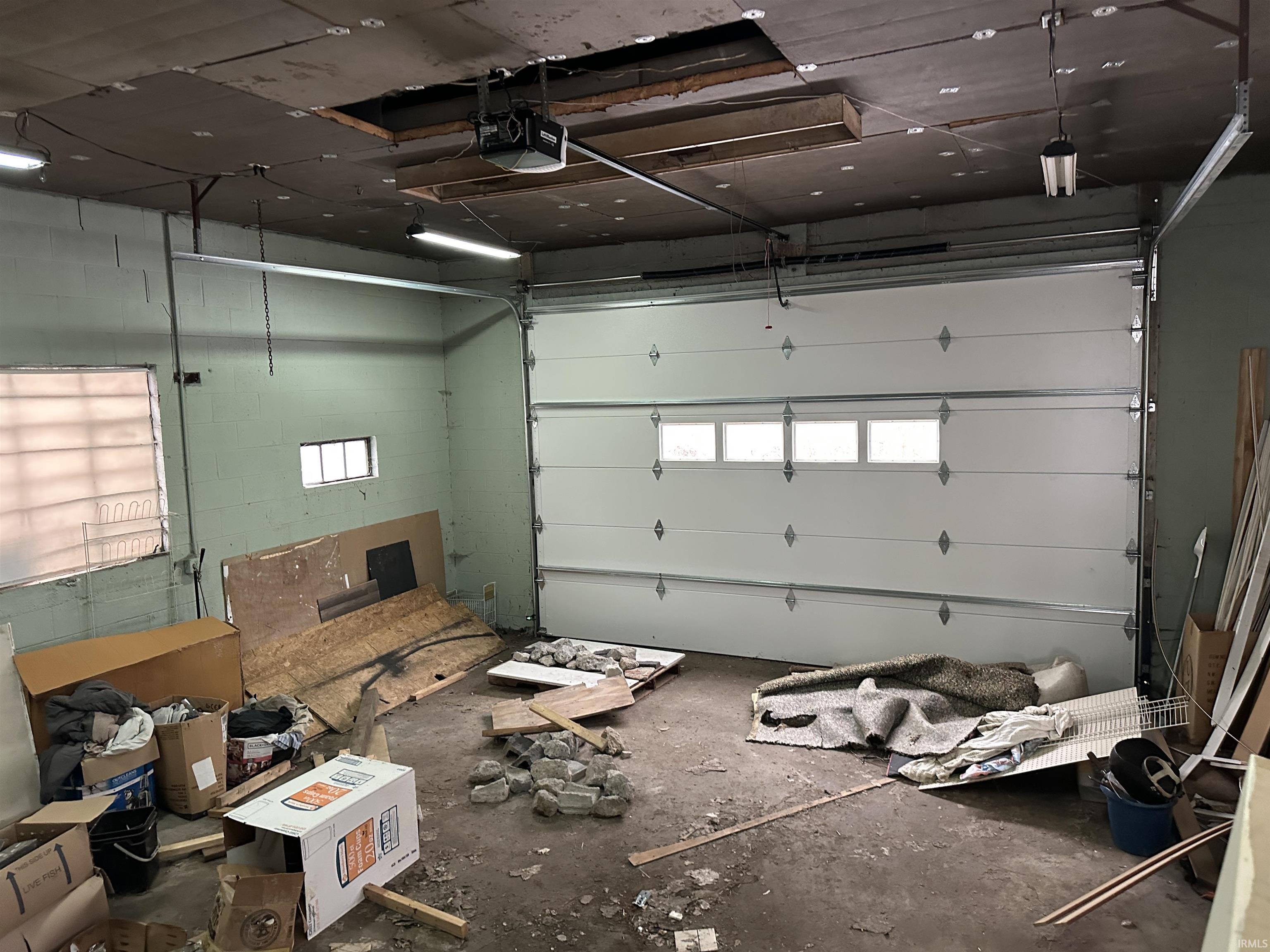 Garage featuring concrete block wall and a garage door opener