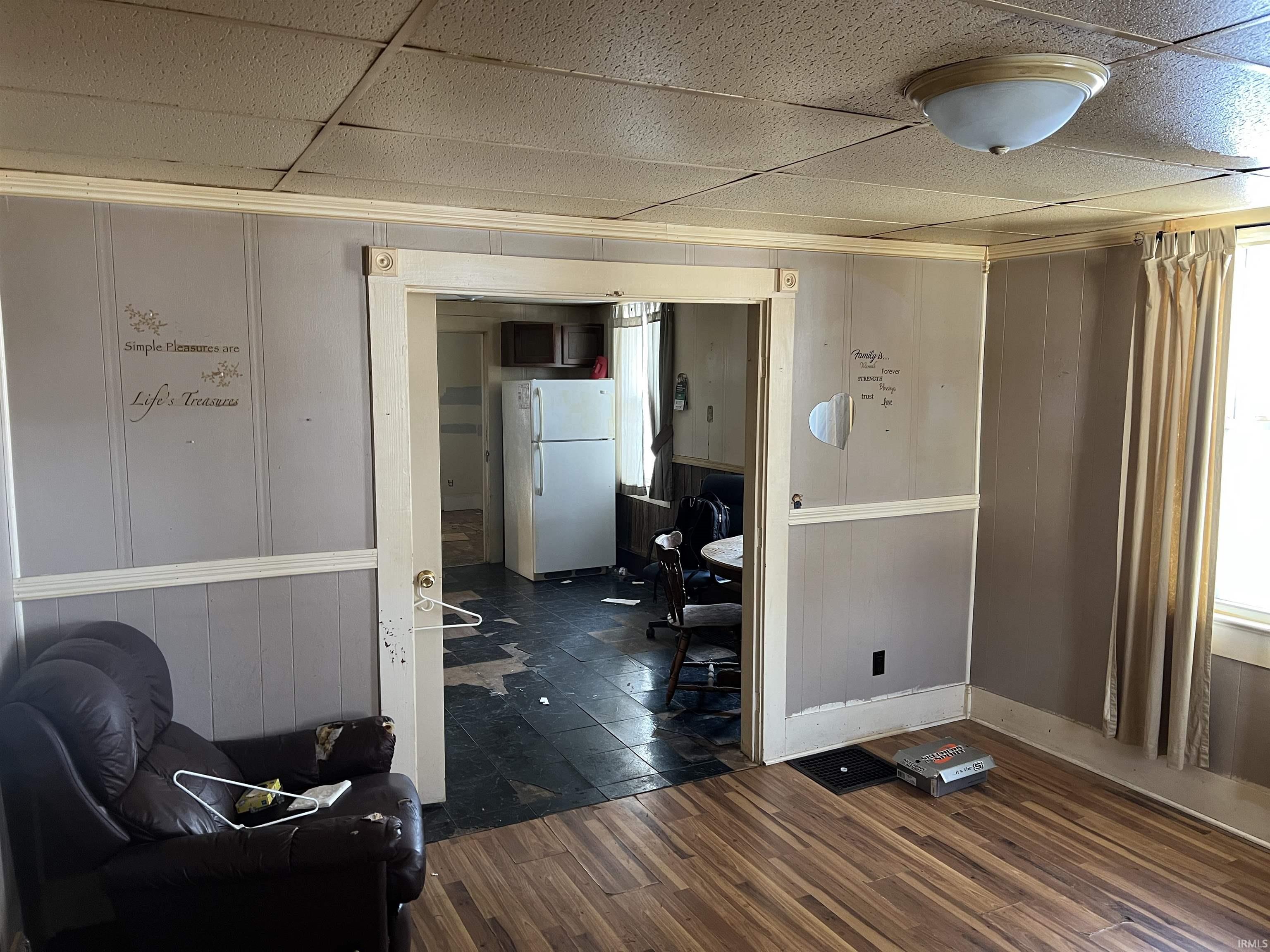Interior space with dark wood finished floors, a decorative wall, a paneled ceiling, and wood walls