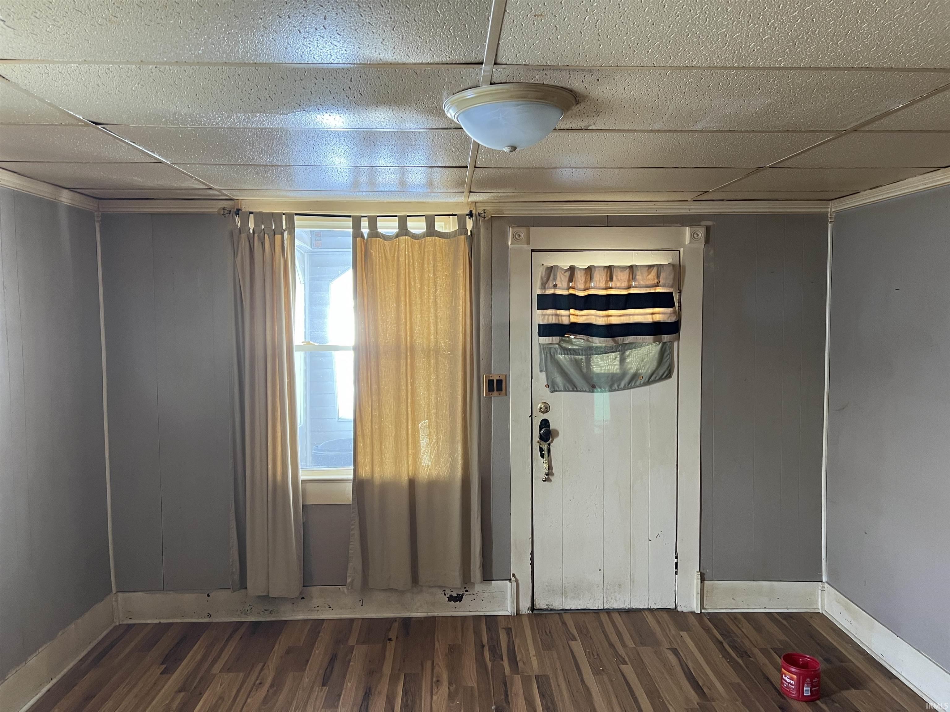 Unfurnished room featuring a paneled ceiling, dark wood-style flooring, and crown molding