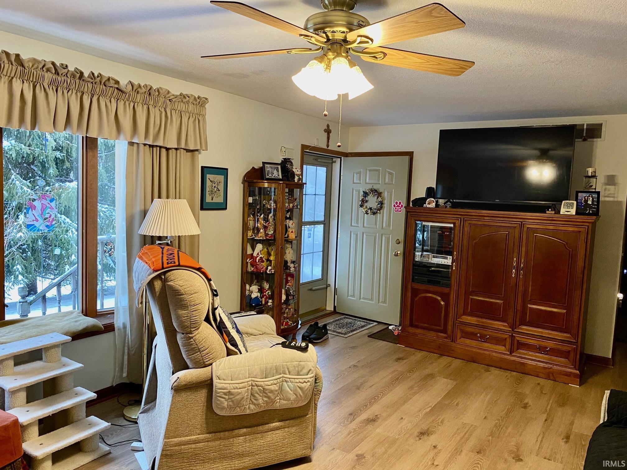 Living area with light wood-style flooring and a ceiling fan