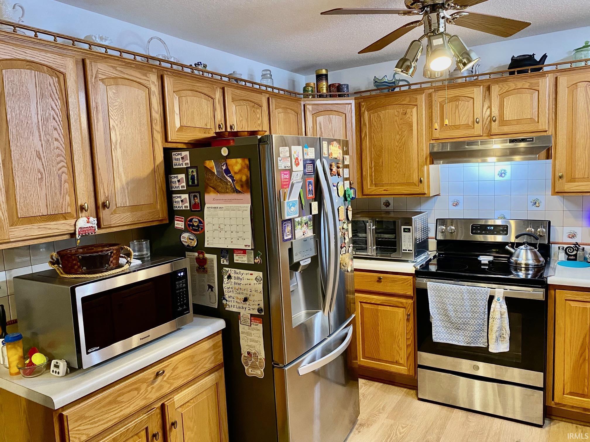 Kitchen with appliances with stainless steel finishes, brown cabinets, decorative backsplash, light countertops, and a textured ceiling