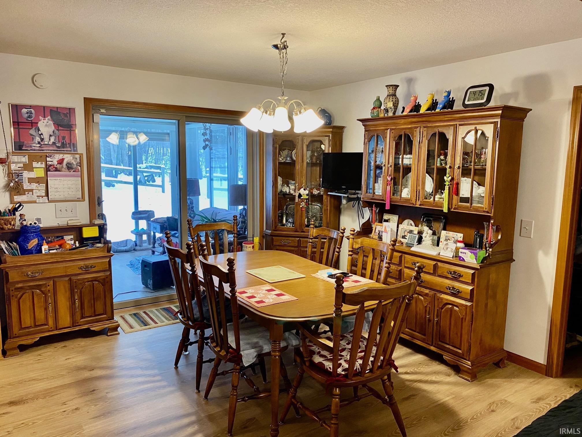 Dining space featuring a chandelier, a textured ceiling, and light wood-type flooring