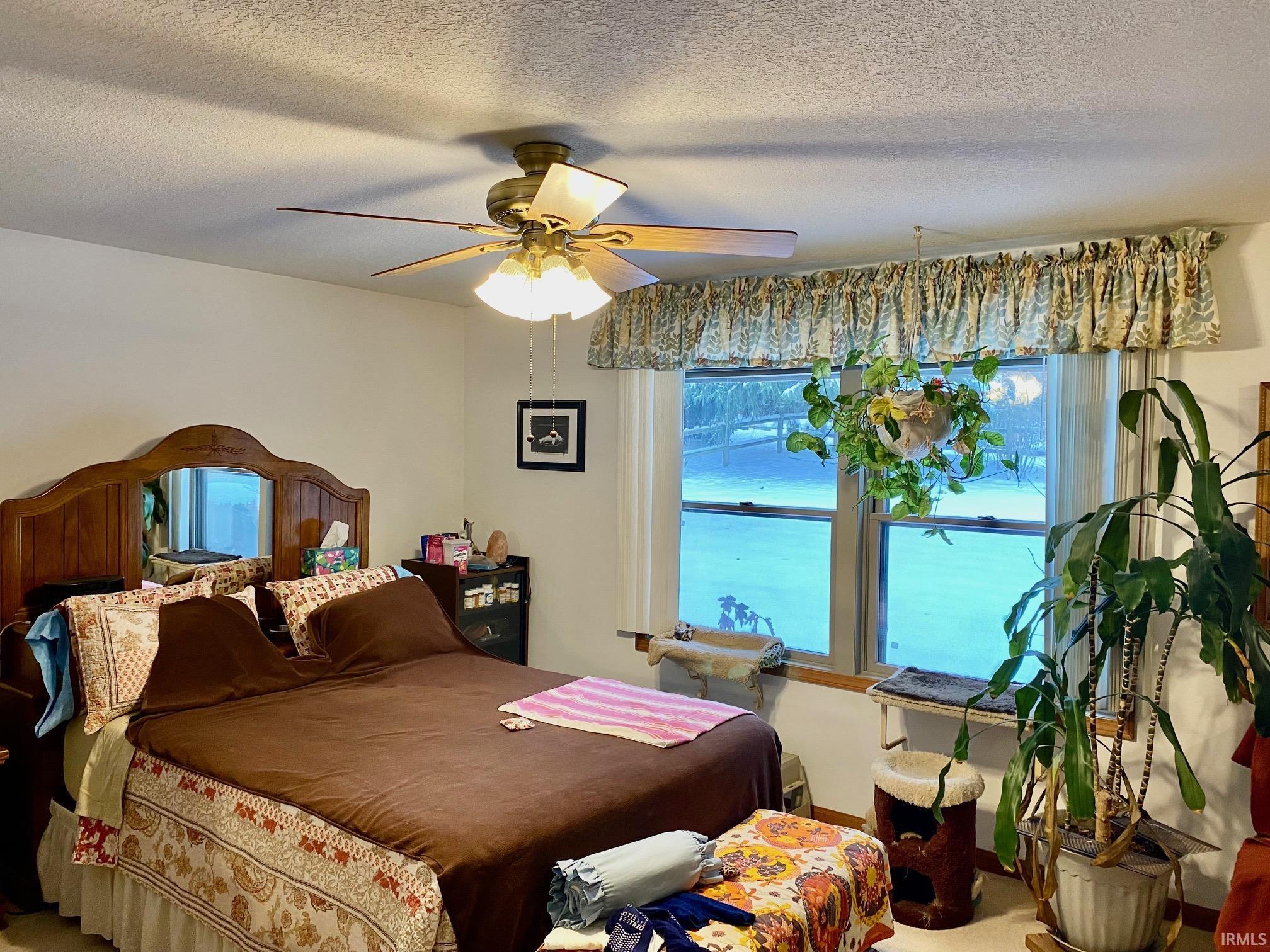 Carpeted bedroom with a textured ceiling and a ceiling fan