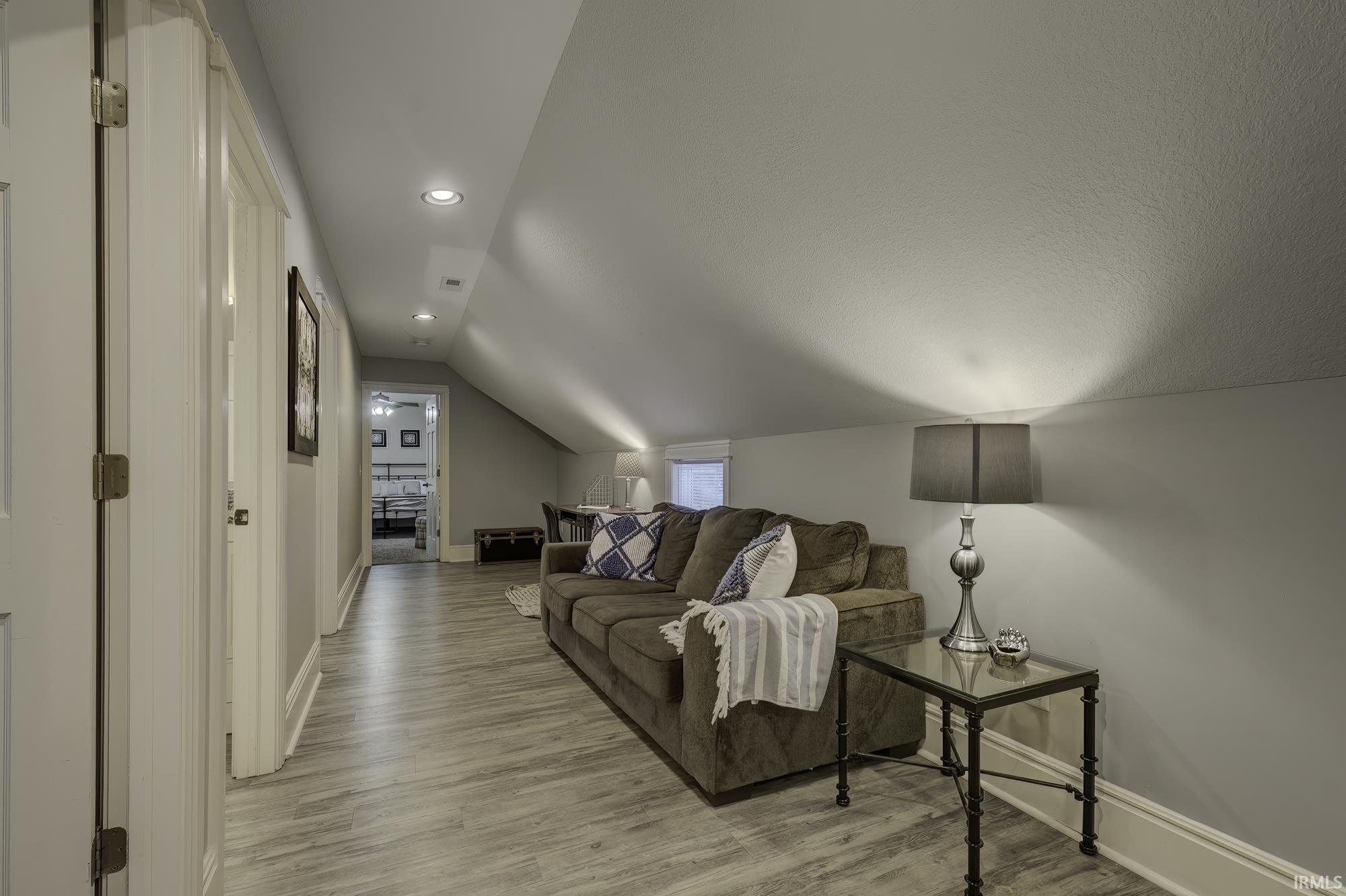 Living room with lofted ceiling, light wood-style floors, and recessed lighting