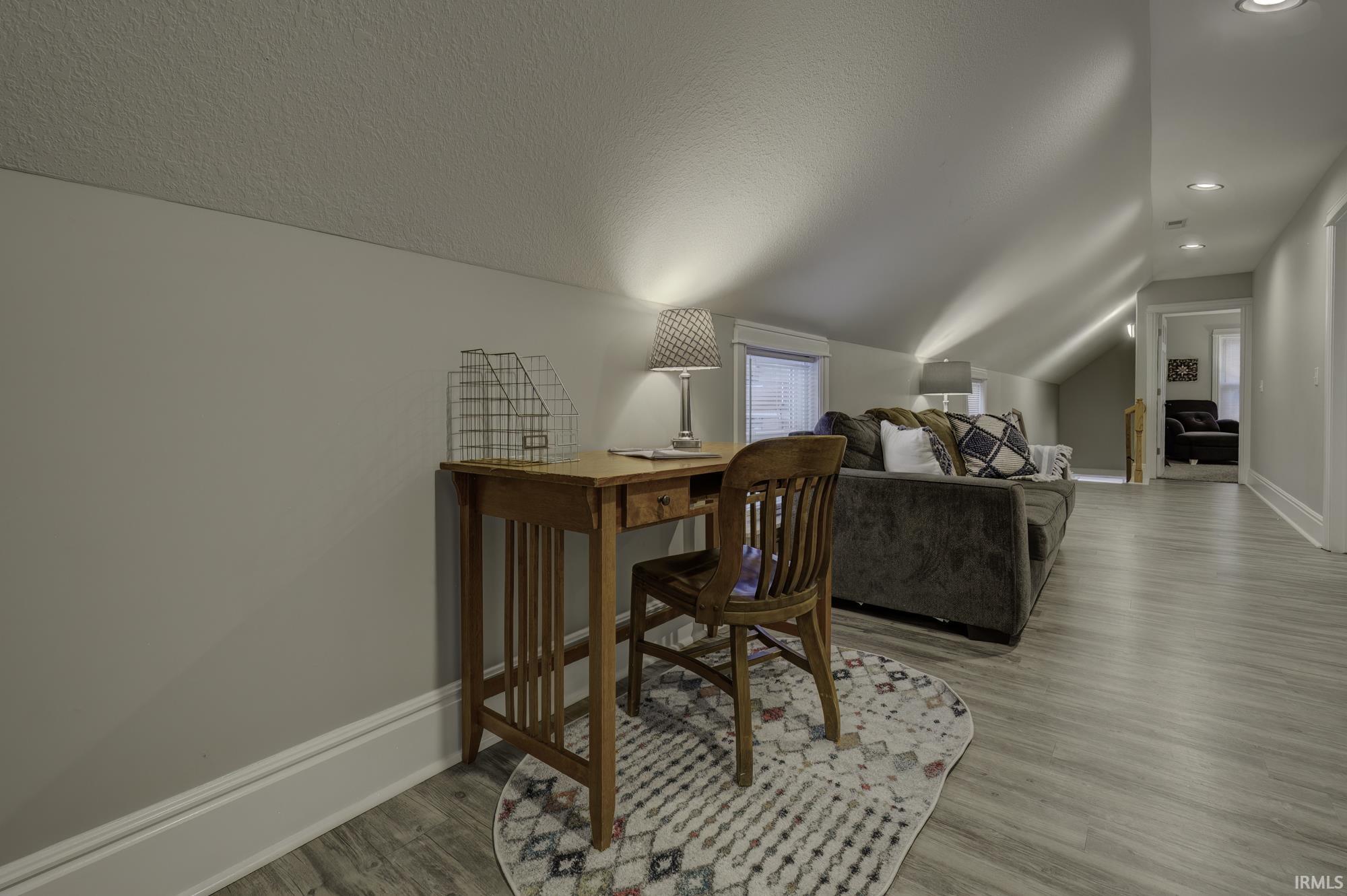 Office featuring light wood finished floors, lofted ceiling, and a textured ceiling
