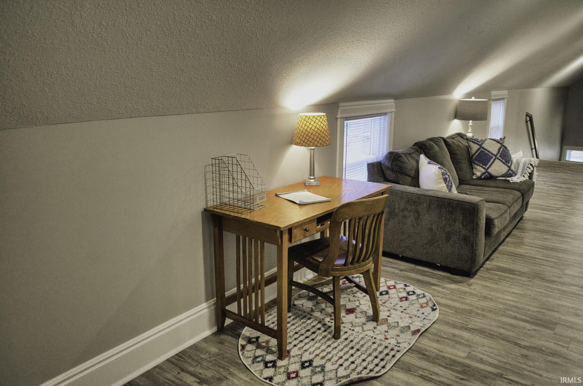 Office with a textured ceiling, dark wood finished floors, and lofted ceiling