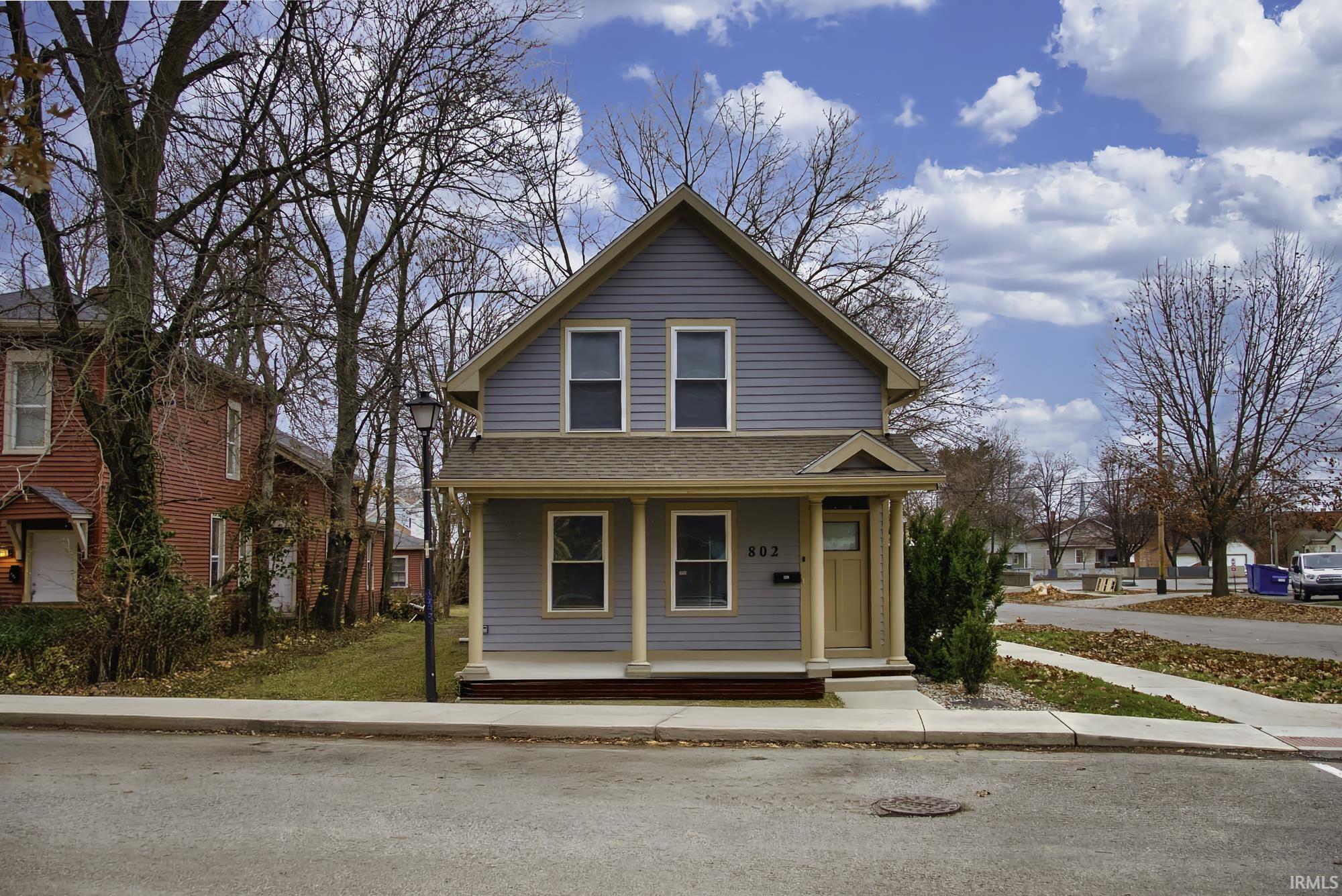 View of front of house with covered porch and roof with shingles