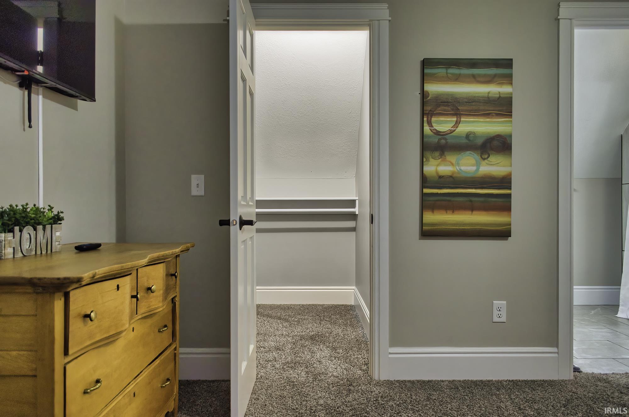 Corridor featuring dark colored carpet and baseboards