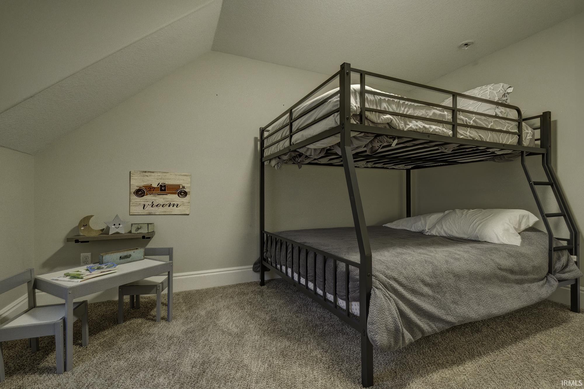 Bedroom with light colored carpet and vaulted ceiling