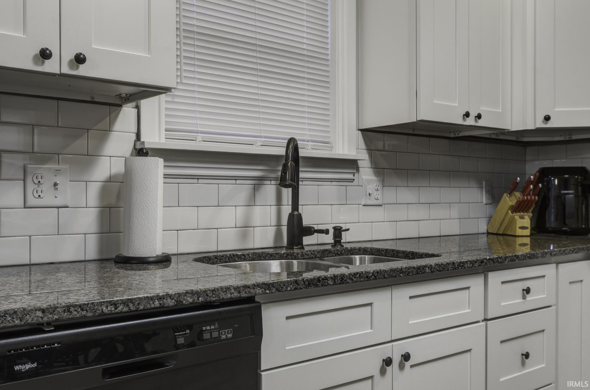 Kitchen featuring dishwasher, white cabinets, backsplash, and dark stone countertops