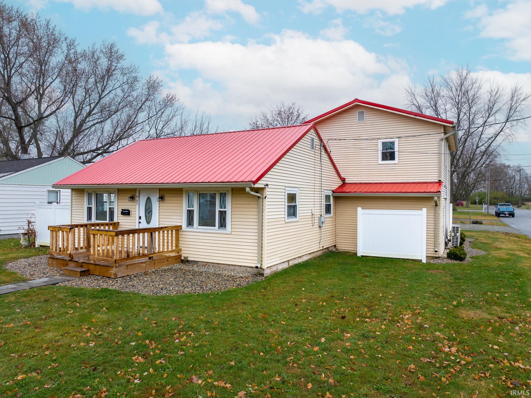 Rear view of house featuring a yard, a metal roof, a deck, and an attached garage