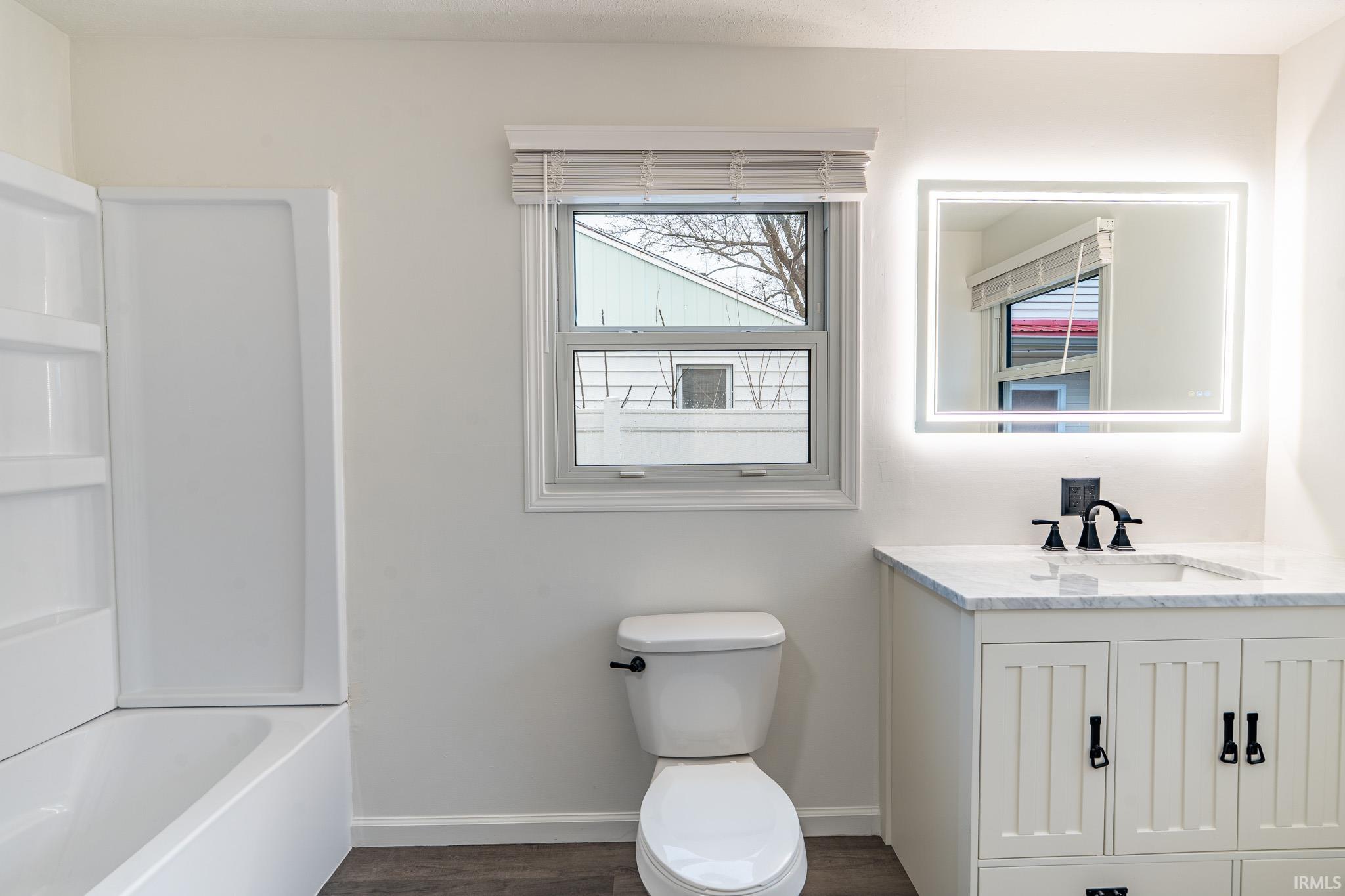 Bathroom with vanity, dark wood-type flooring, and tub / shower combination