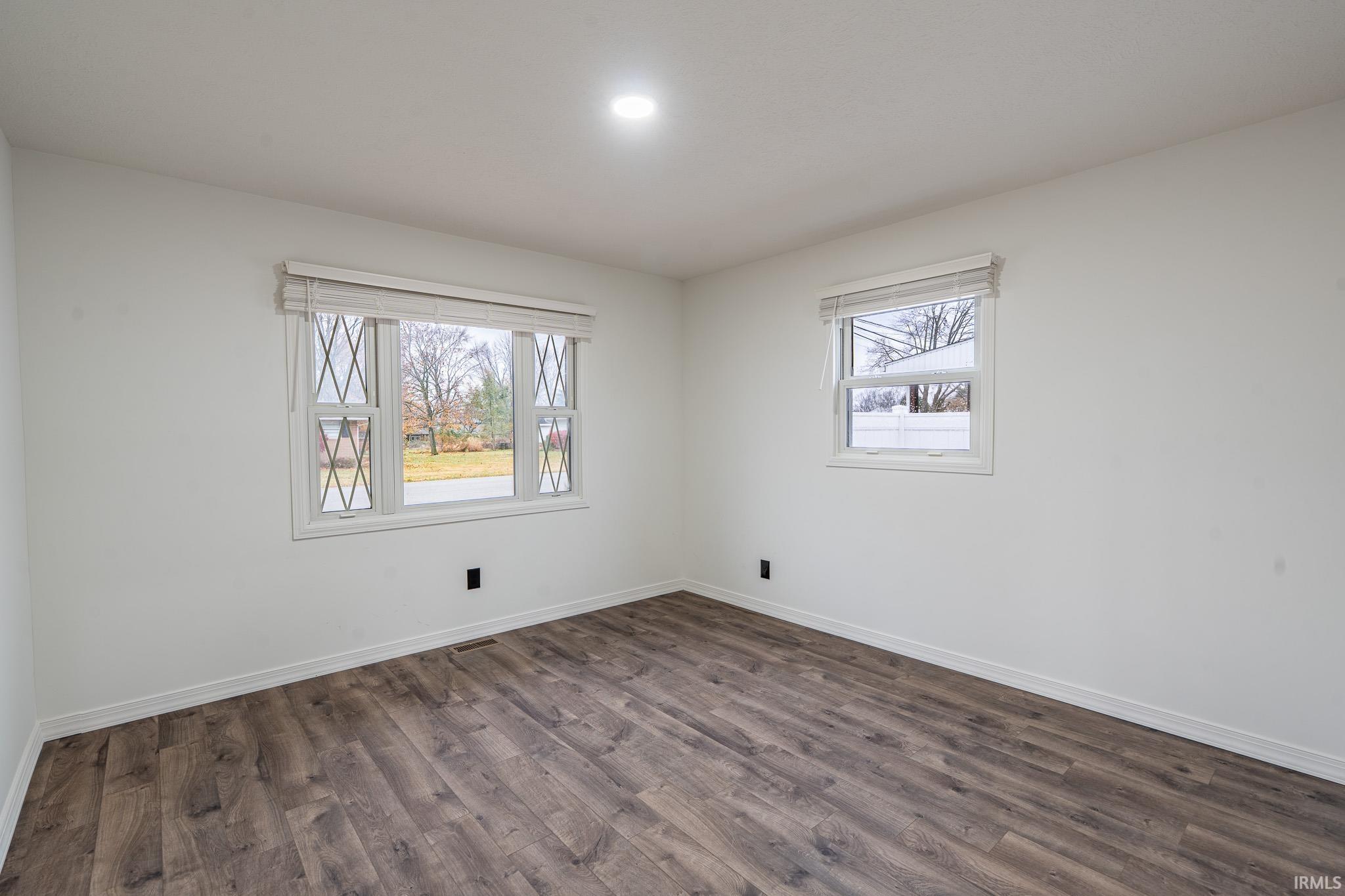 Empty room with dark wood-style floors and baseboards
