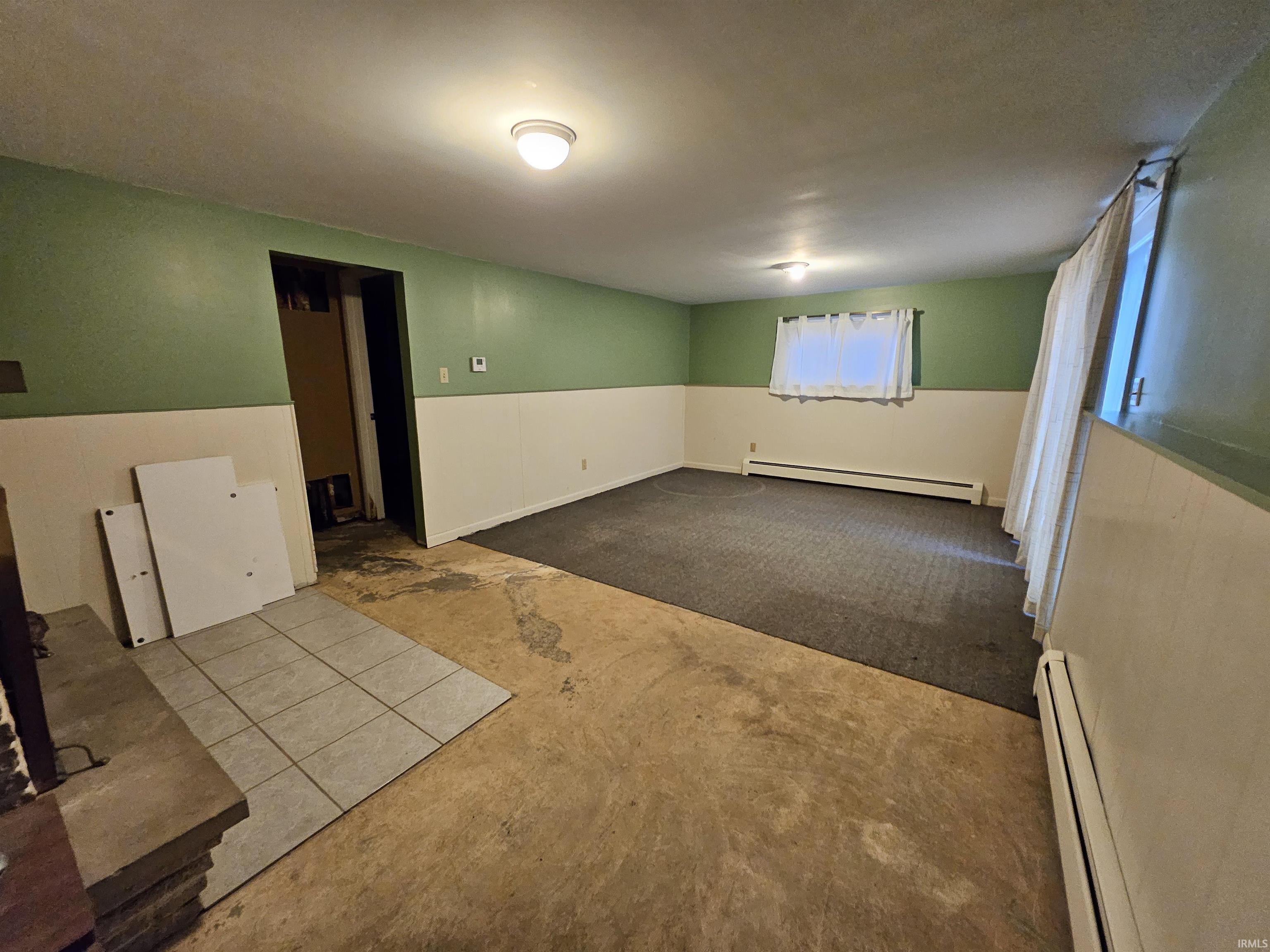 Empty room with carpet flooring and baseboard heating
