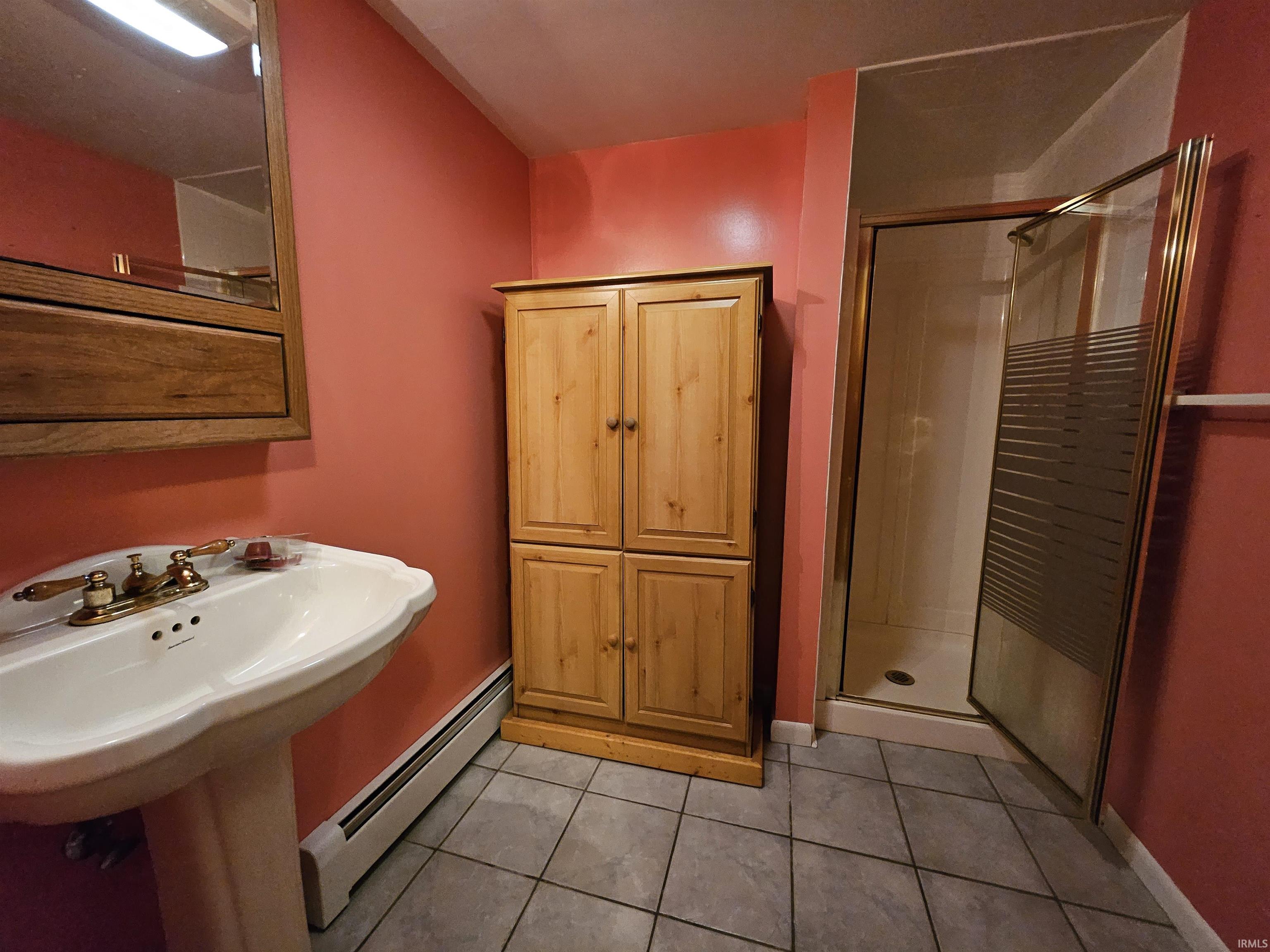 Bathroom with a baseboard radiator, a shower stall, and light tile patterned floors