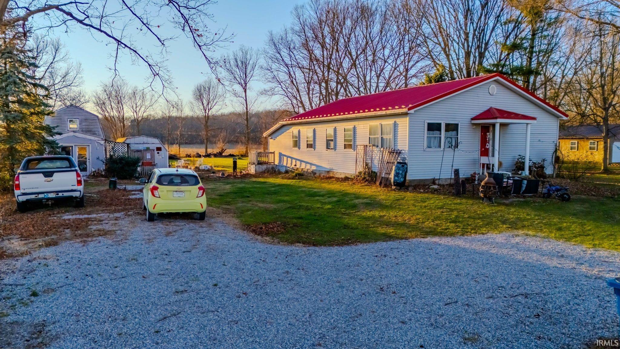 View of front of home with a front lawn, a metal roof, and driveway