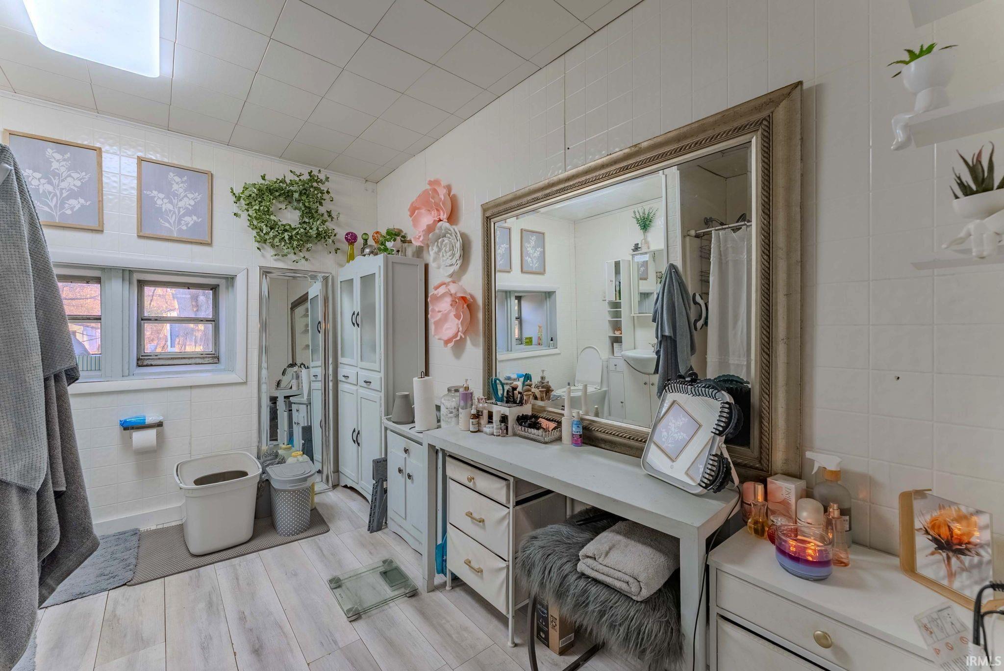 Bathroom featuring tile walls, light wood-style floors, vanity, and curtained shower