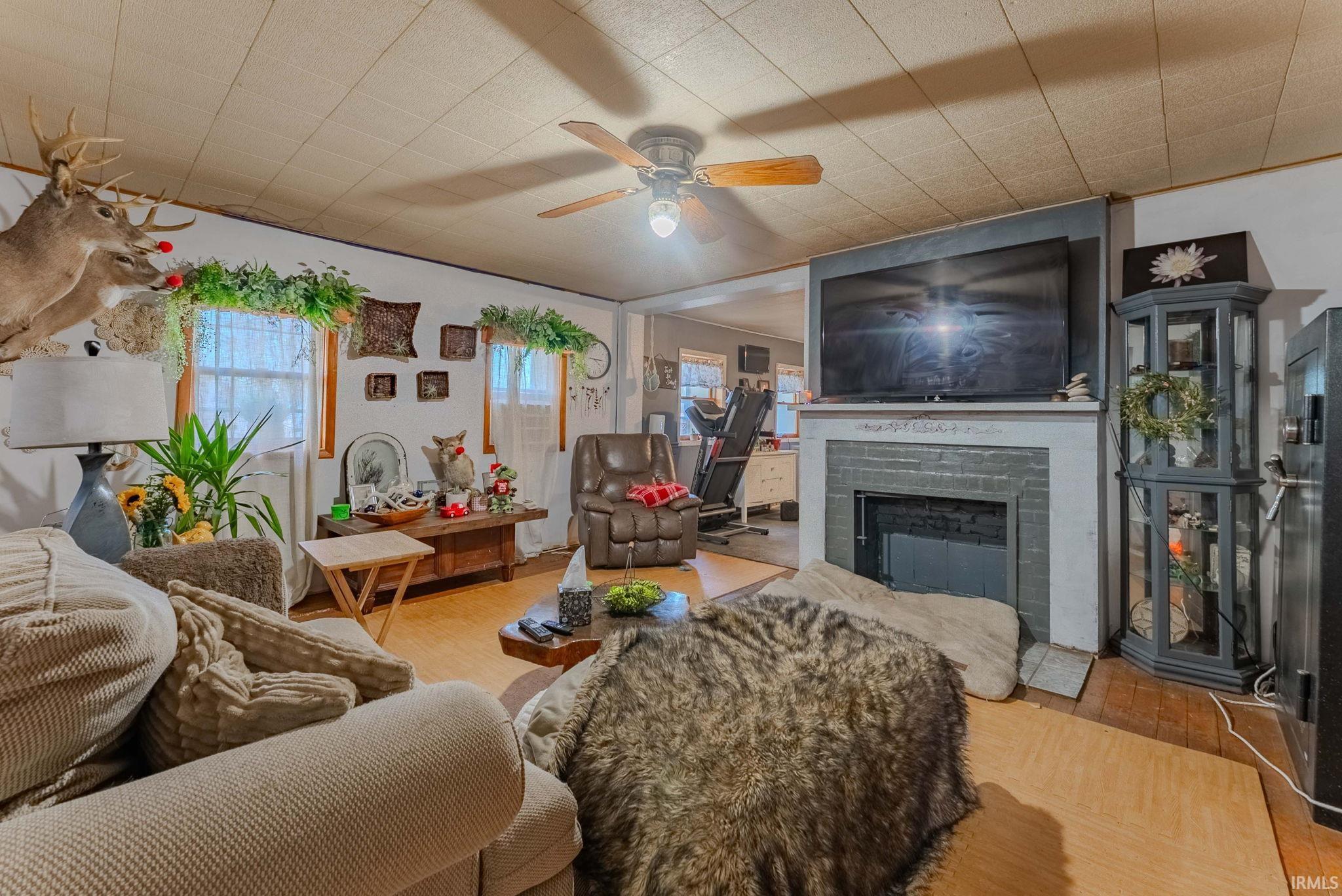 Living room featuring wood finished floors, a fireplace, and a ceiling fan