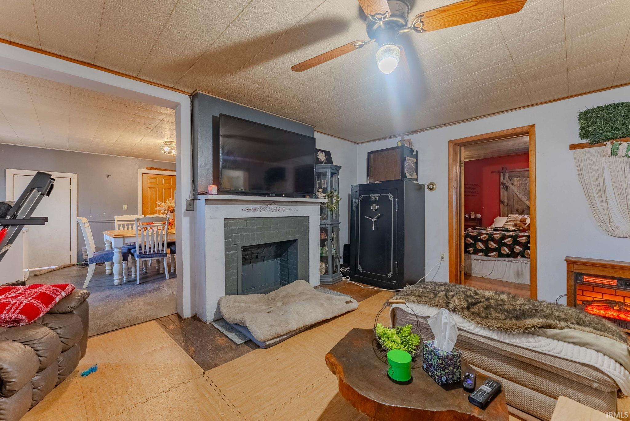 Living room featuring a brick fireplace and a ceiling fan