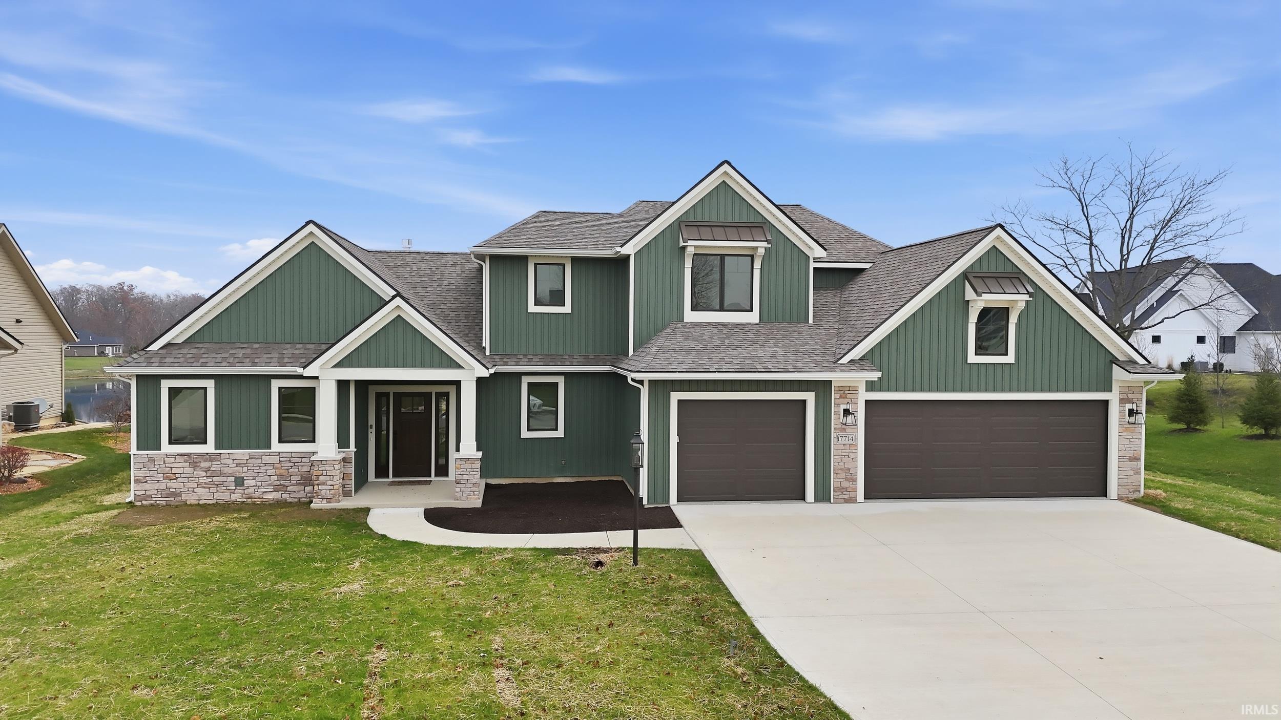 Craftsman house with roof with shingles, stone siding, a front yard, and concrete driveway