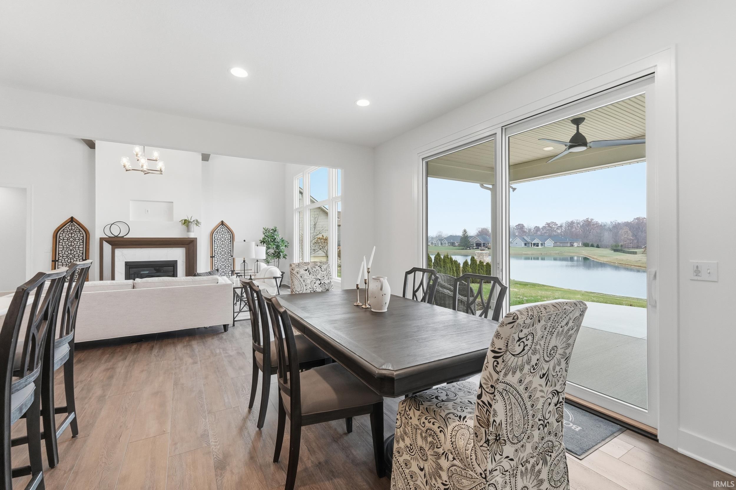 Dining space featuring a fireplace, light wood finished floors, a water view, plenty of natural light, and recessed lighting