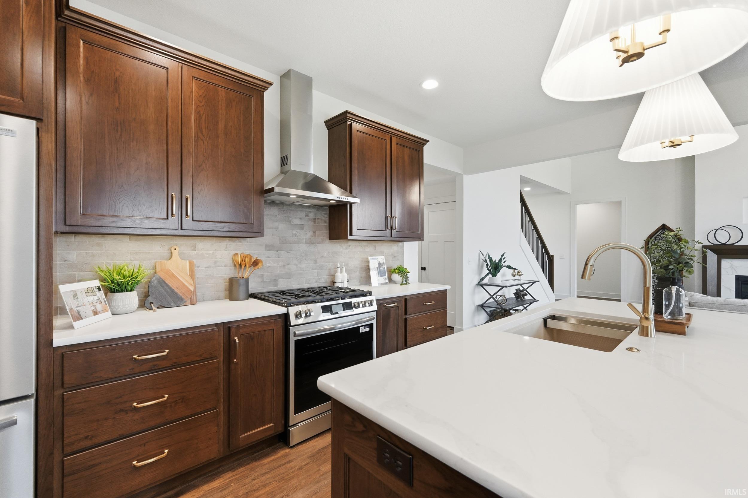 Kitchen featuring gas stove, wall chimney exhaust hood, backsplash, dark wood-style flooring, and recessed lighting