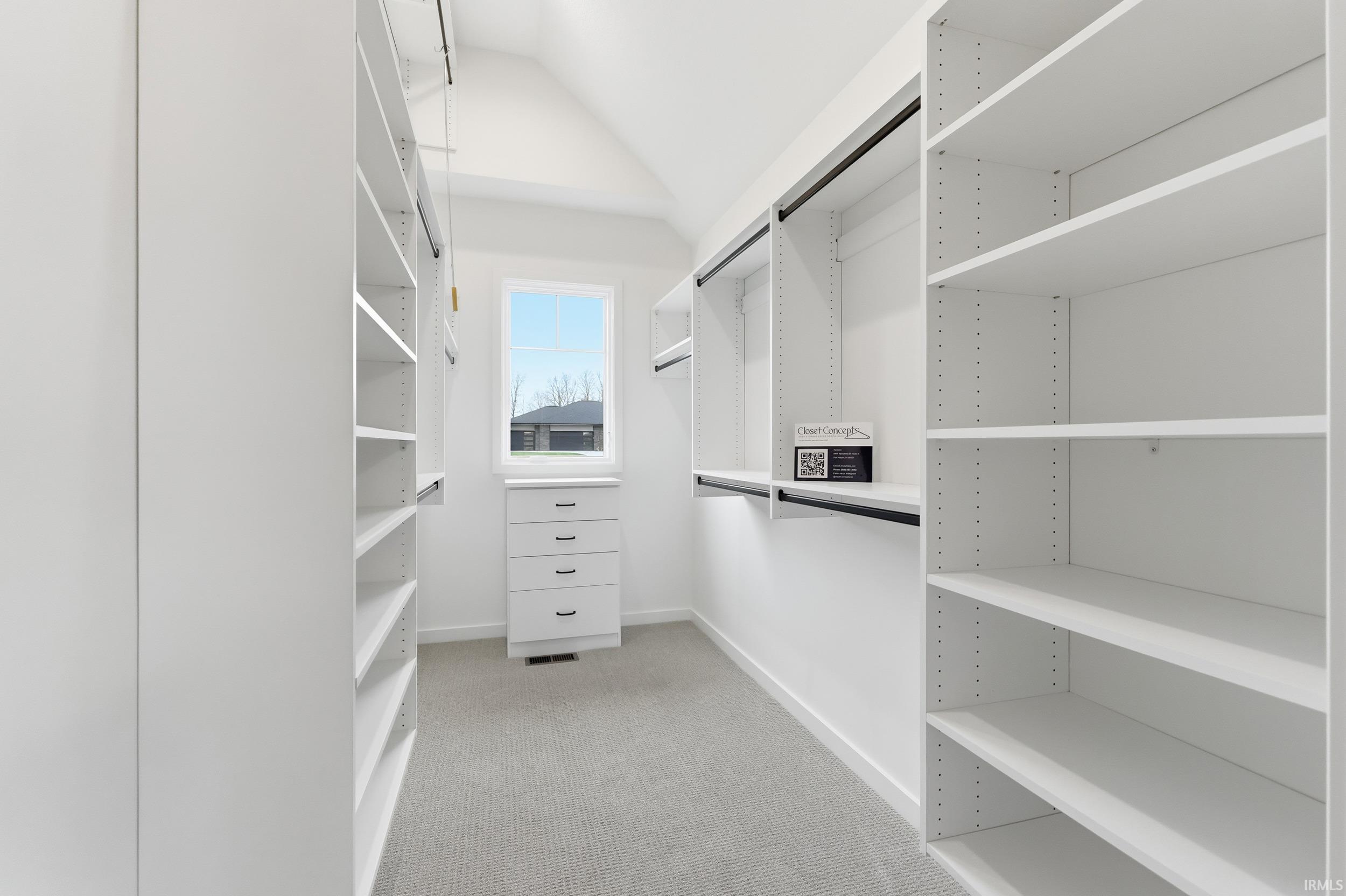 Spacious closet with light colored carpet and vaulted ceiling