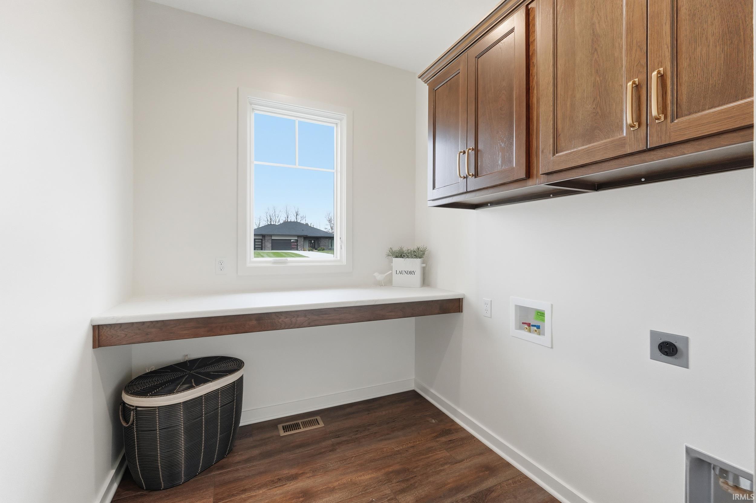 Laundry room featuring dark wood-type flooring, cabinet space, hookup for a washing machine, and hookup for an electric dryer