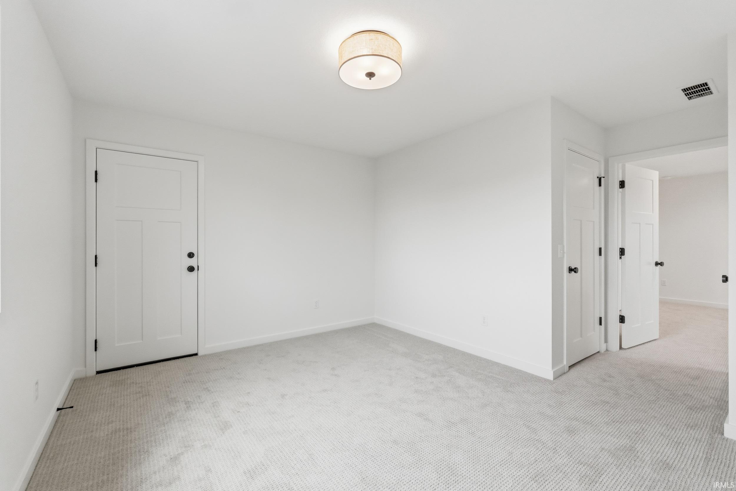 Empty room featuring light carpet and baseboards