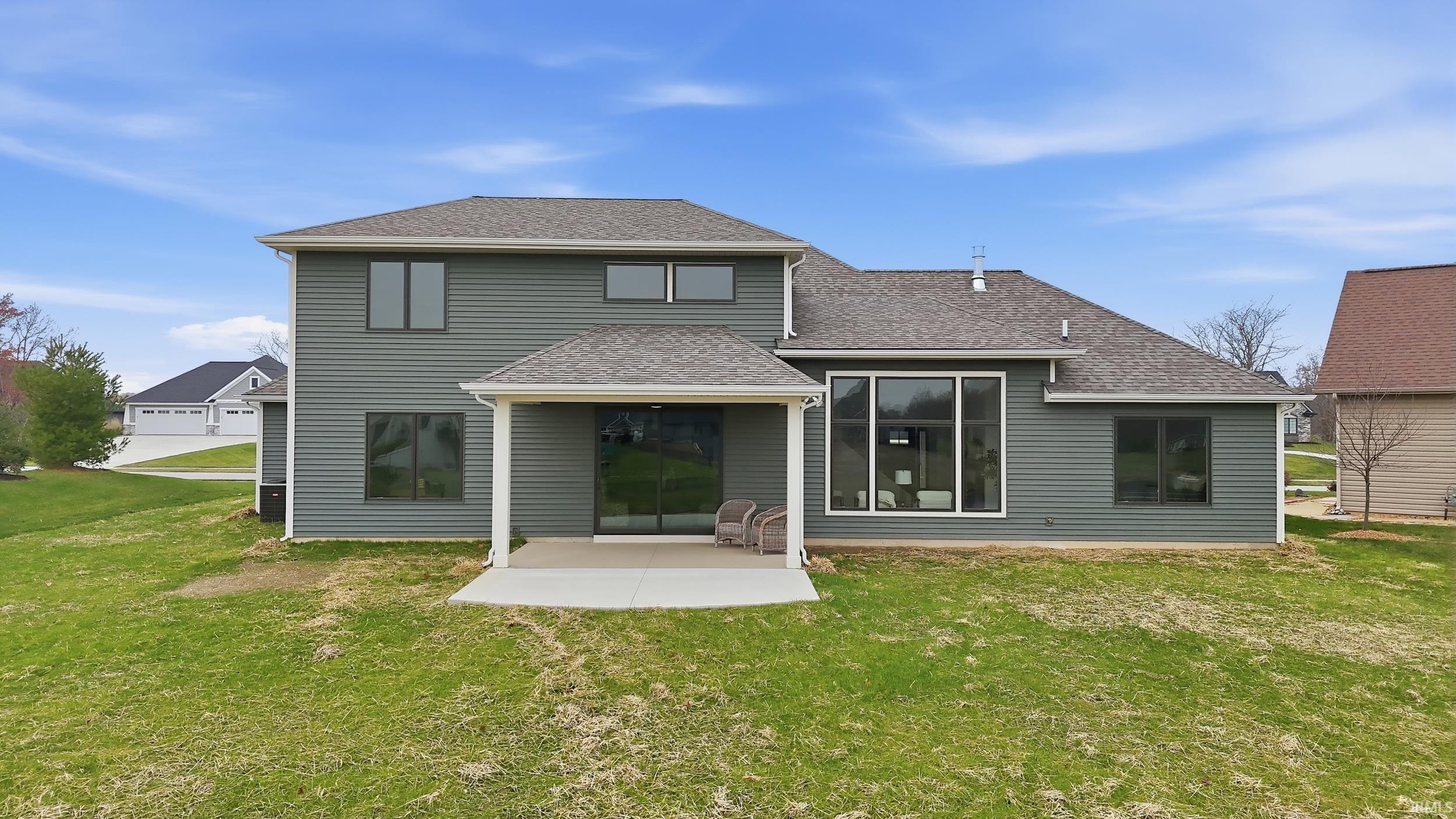 Back of house featuring roof with shingles, a yard, and a patio area