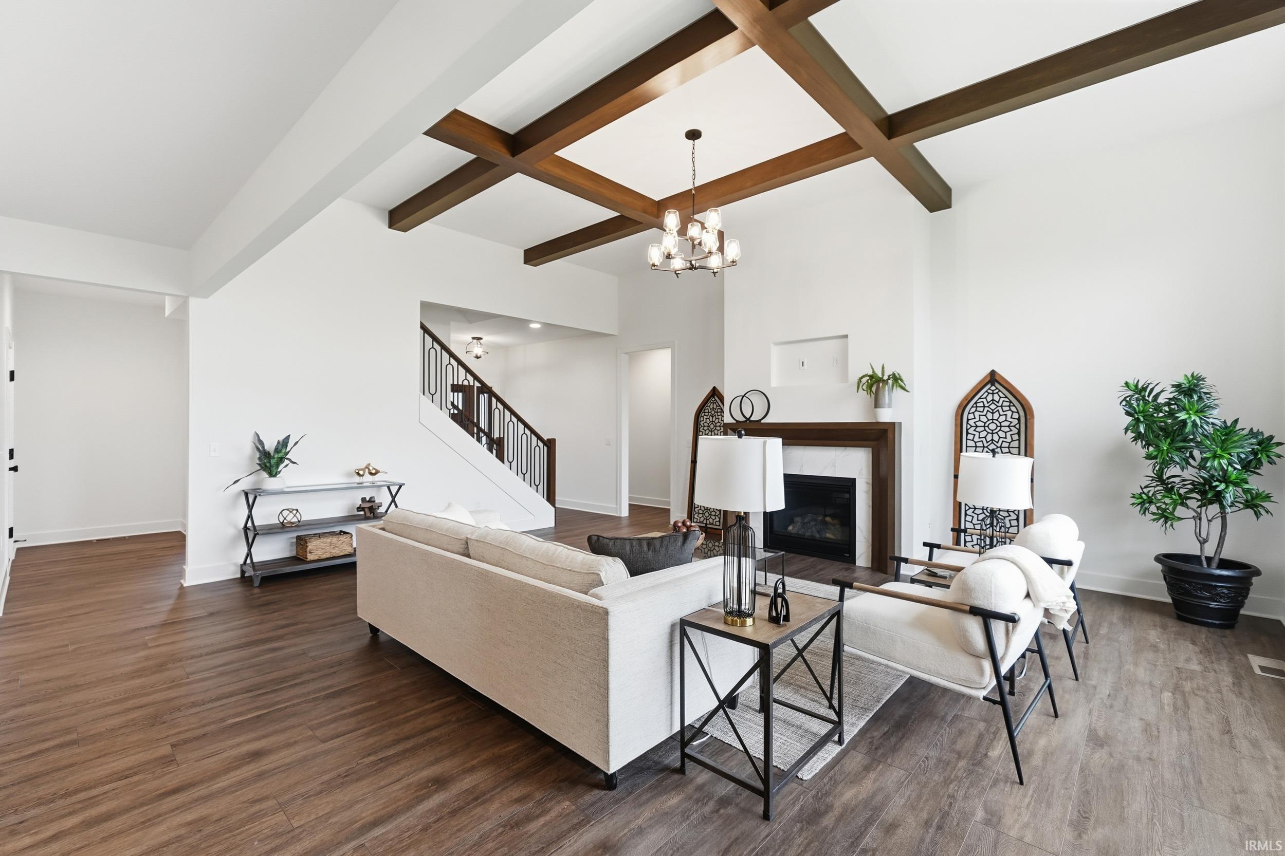 Living area with beam ceiling, a premium fireplace, coffered ceiling, dark wood finished floors, and stairs