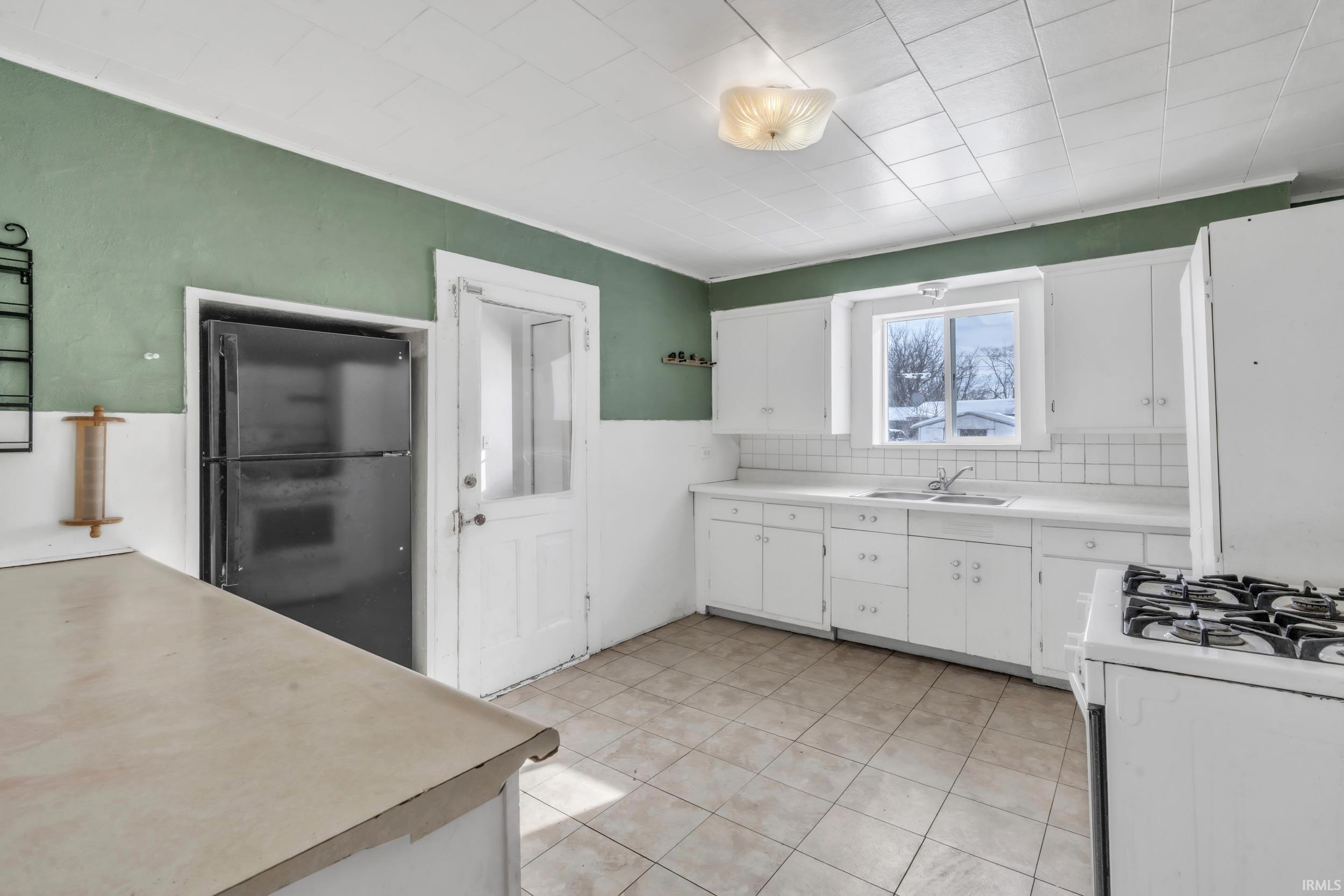 Kitchen featuring white cabinetry, light countertops, white appliances, and light tile patterned flooring