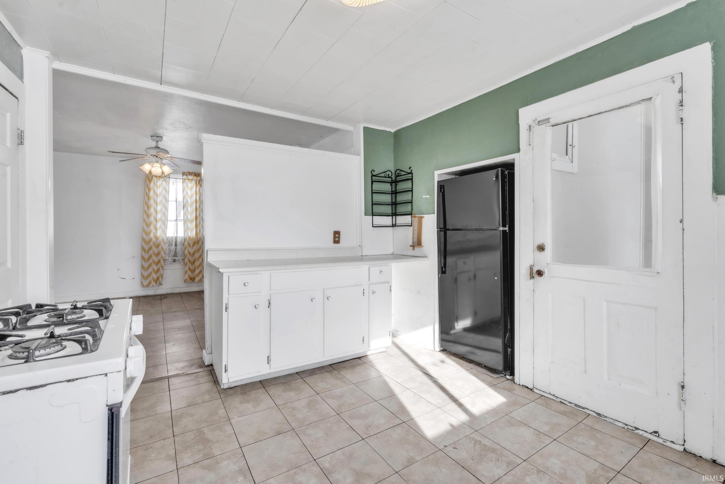 Kitchen featuring white cabinetry, light countertops, white gas range oven, freestanding refrigerator, and light tile patterned floors