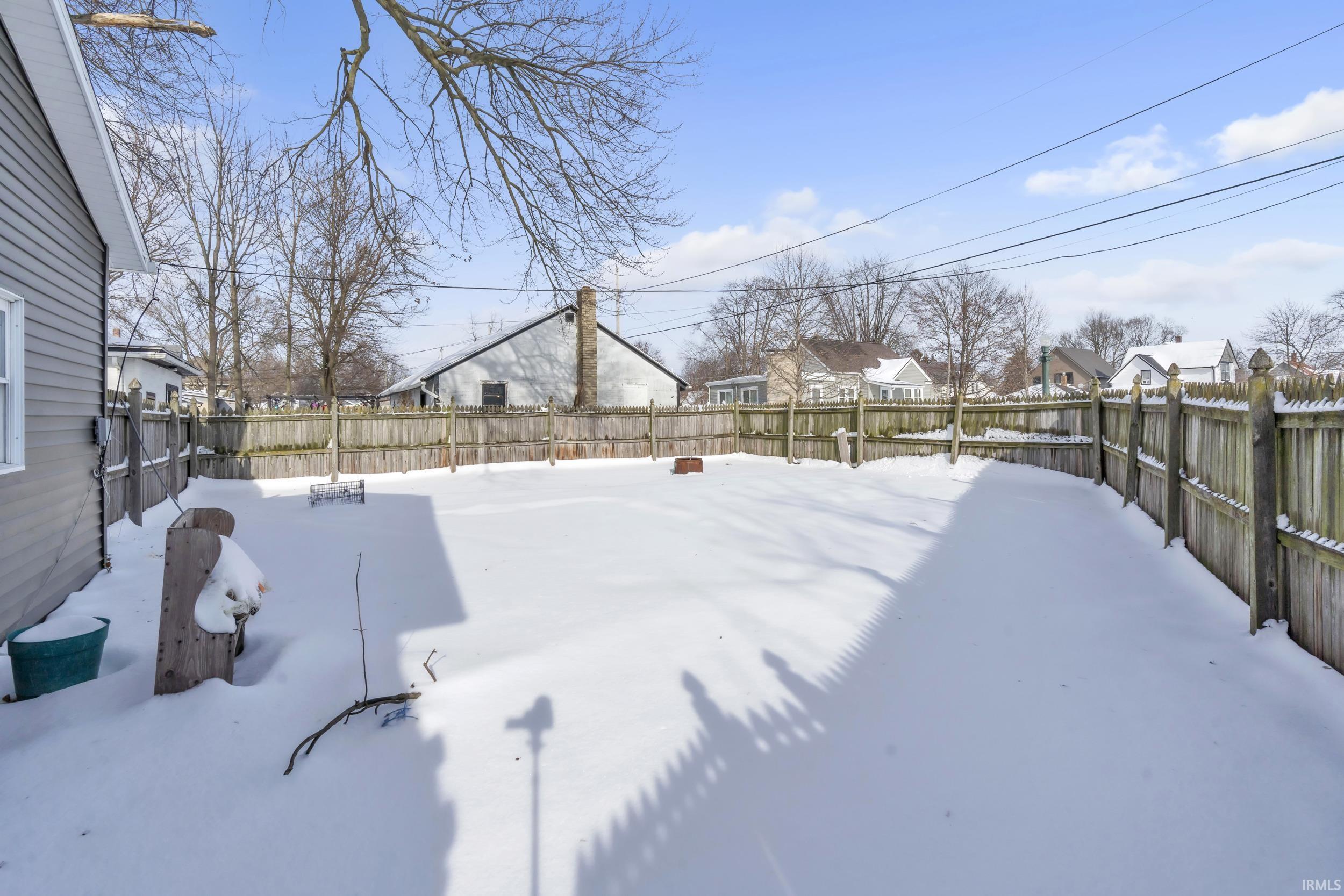Yard layered in snow featuring a fenced backyard and a residential view