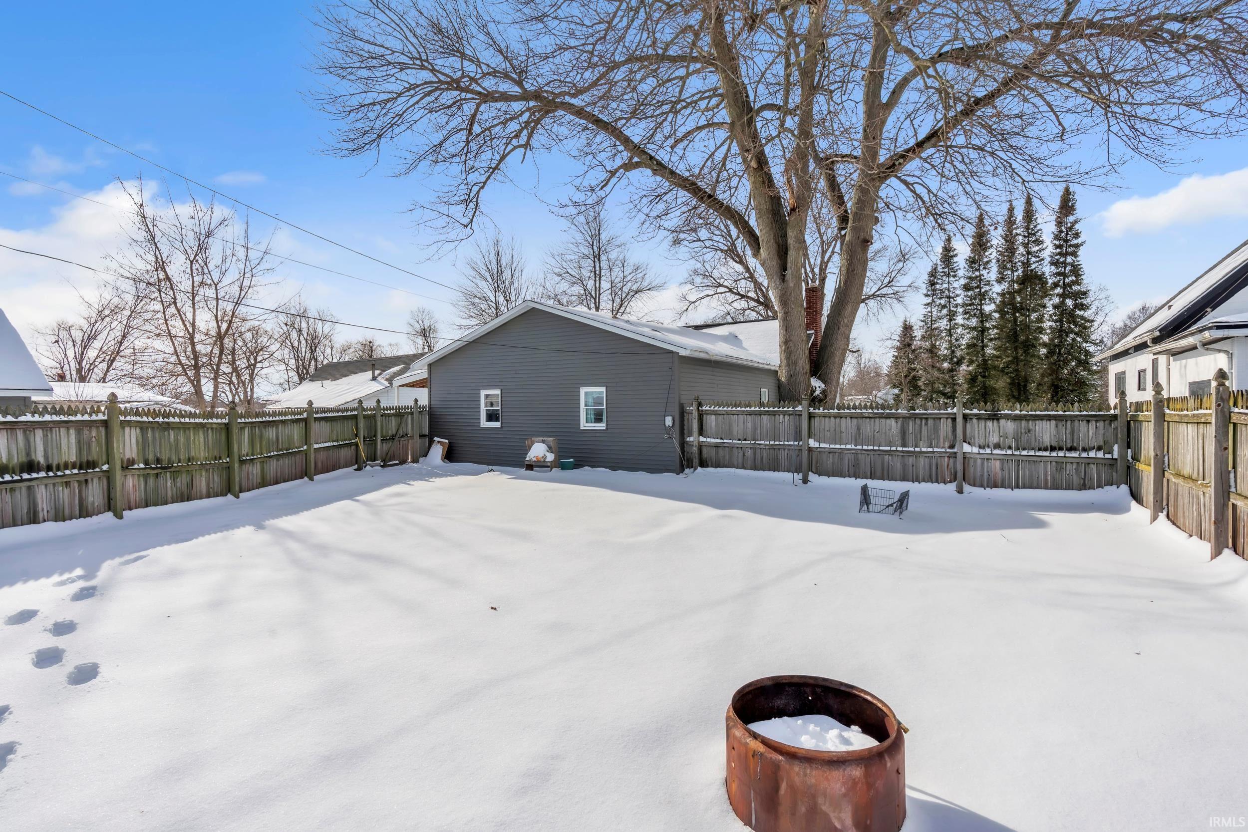 Yard layered in snow featuring a fenced backyard